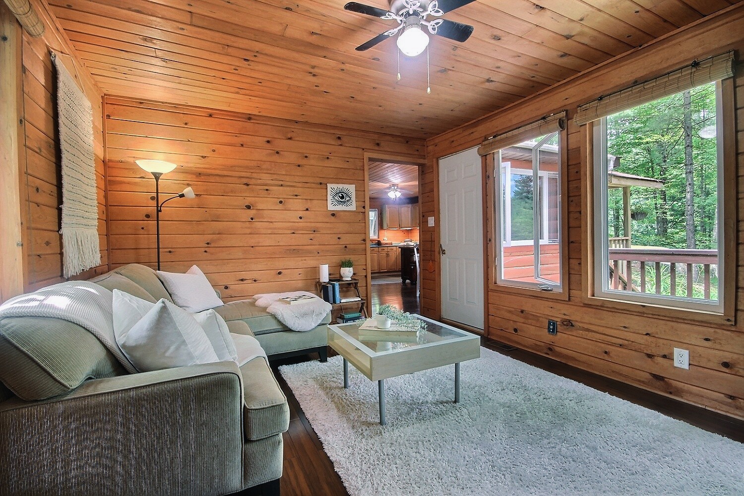 A white couch faces a large window. Between them, a white rug and a coffee table