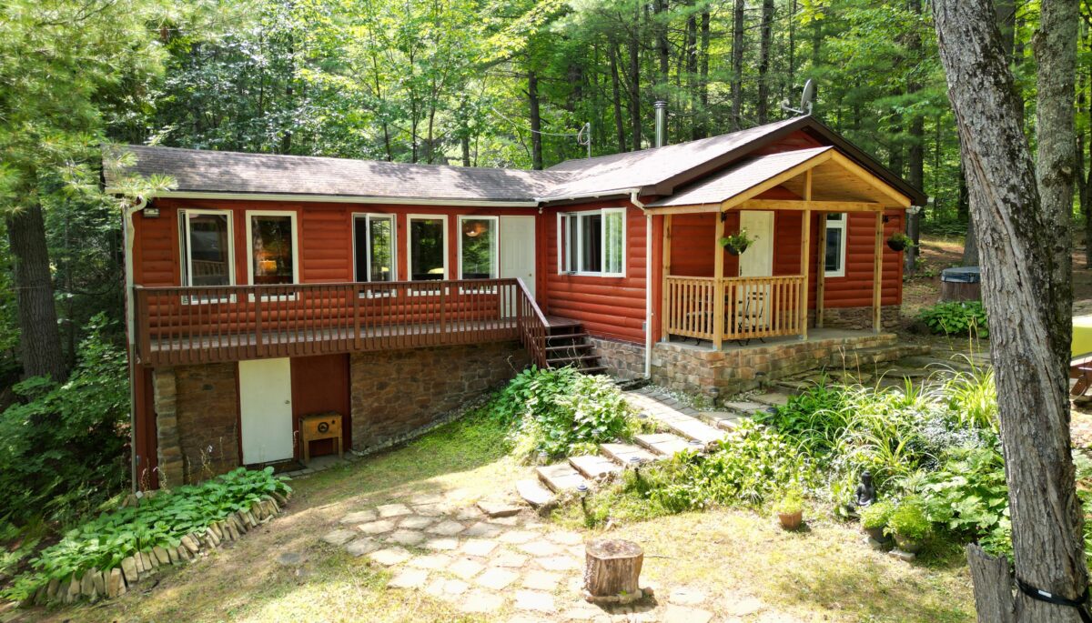 A red panelled bungalow cottage with steps leading up to the front door