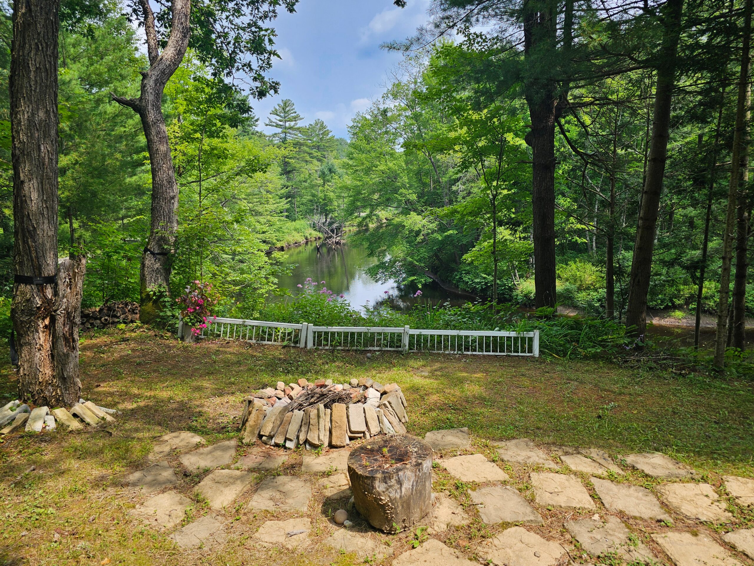A fire pit area on yellow grass. Behind, a brown river