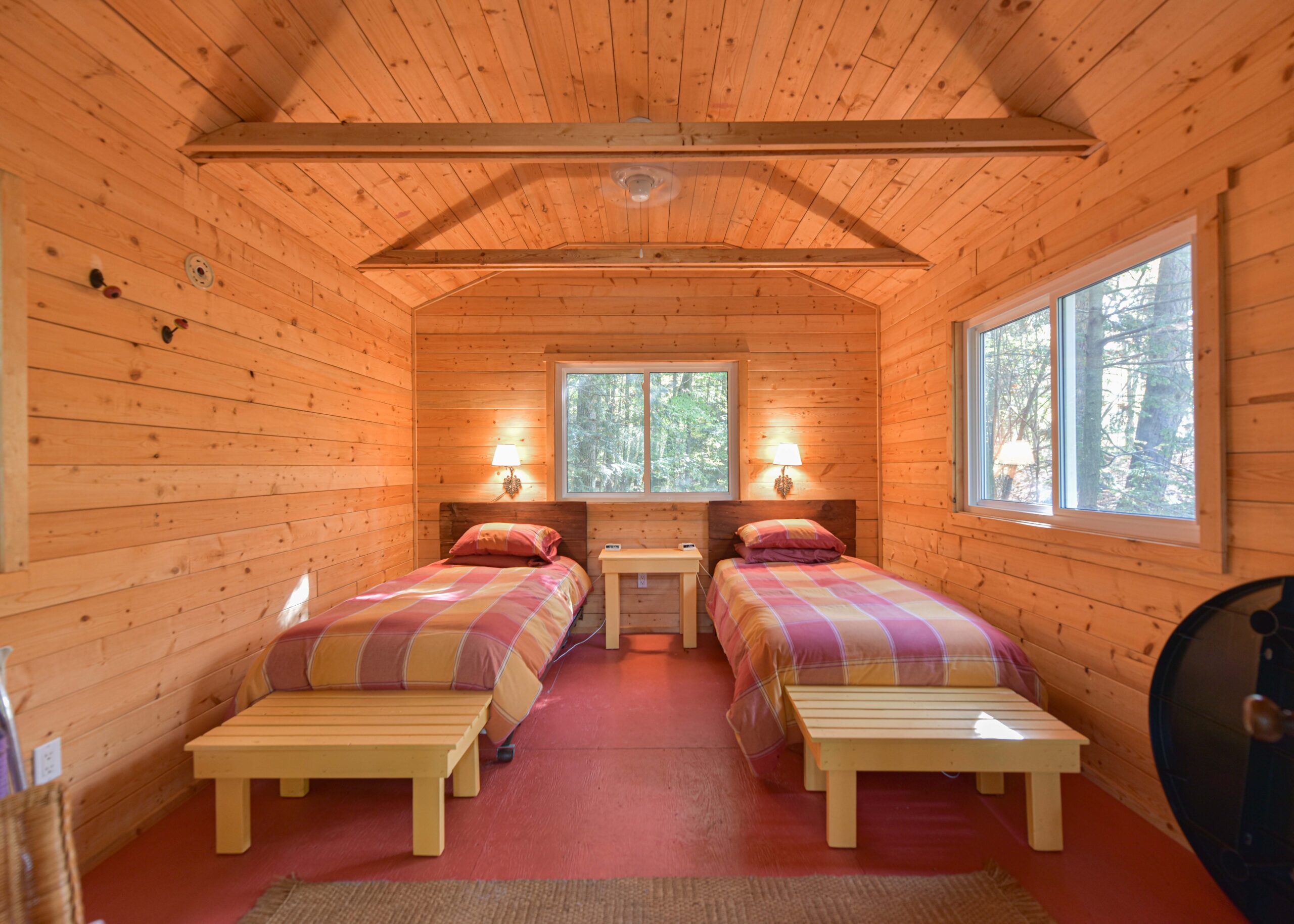 Two twin beds with checkered covers with a small bench at each end next to each other