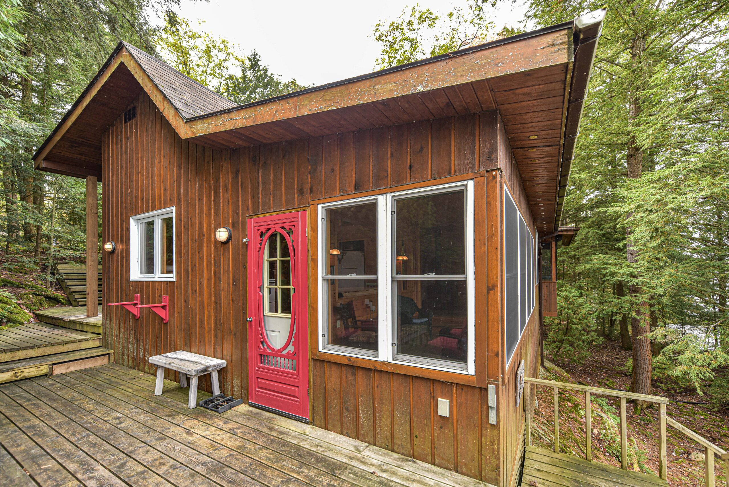 A small wood cottage with a red door and large windows to the right