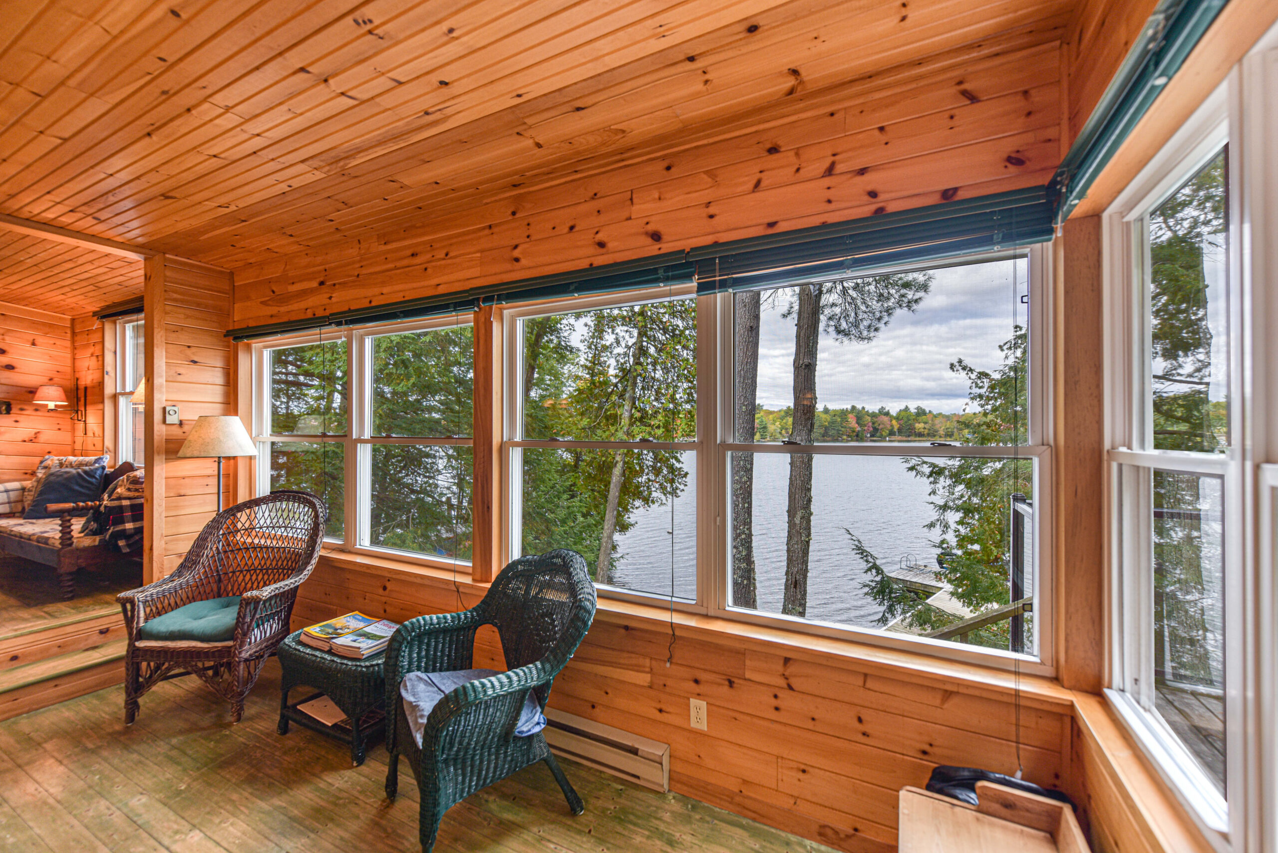 Wicker chairs face away from a wood wall with large windows
