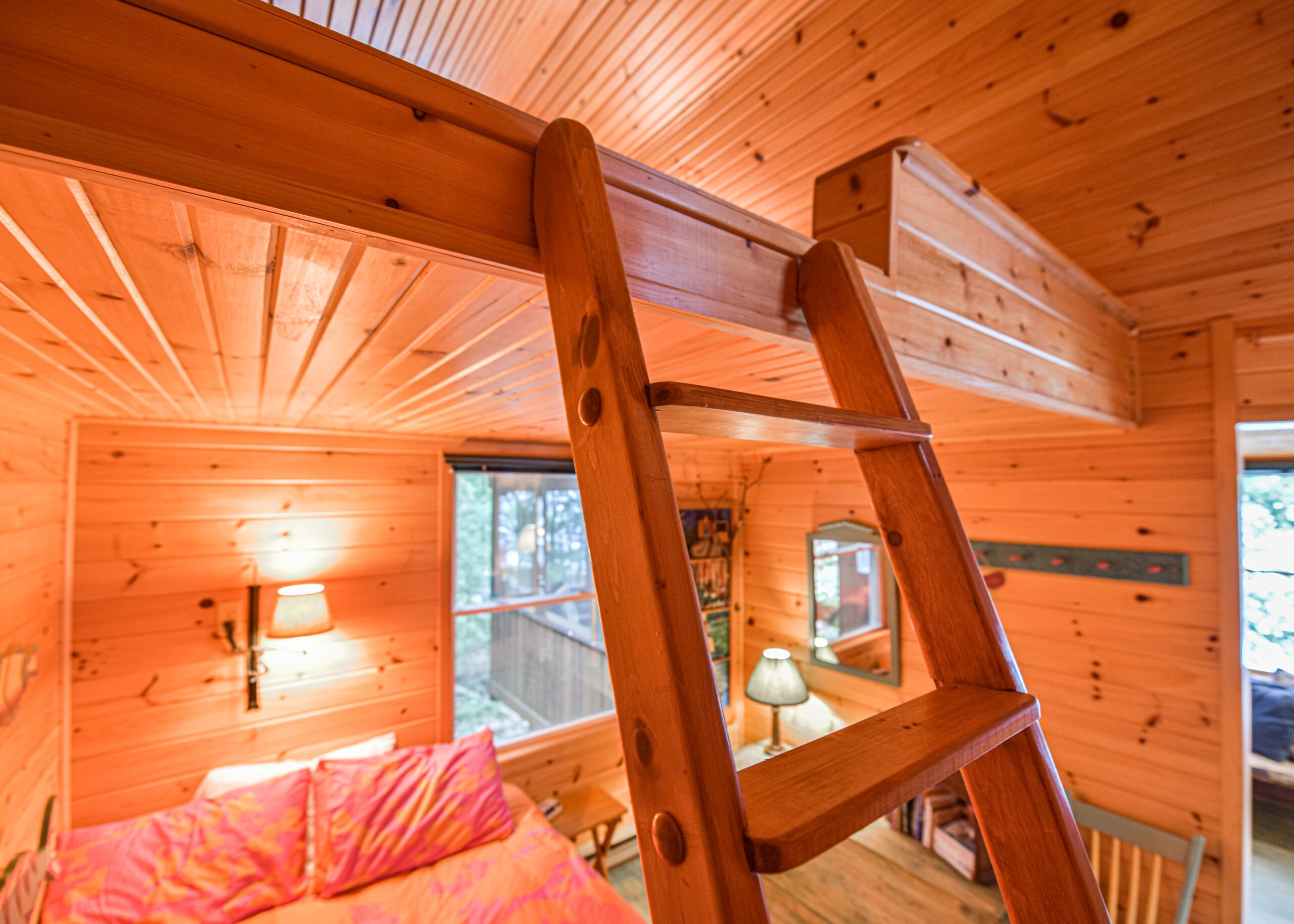 A wood ladder over a pink bed