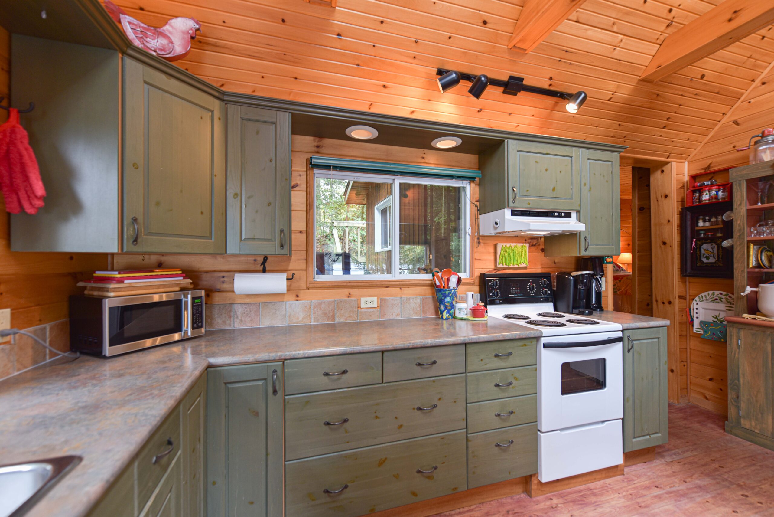 Along one wall, green kitchen cabinets and white oven