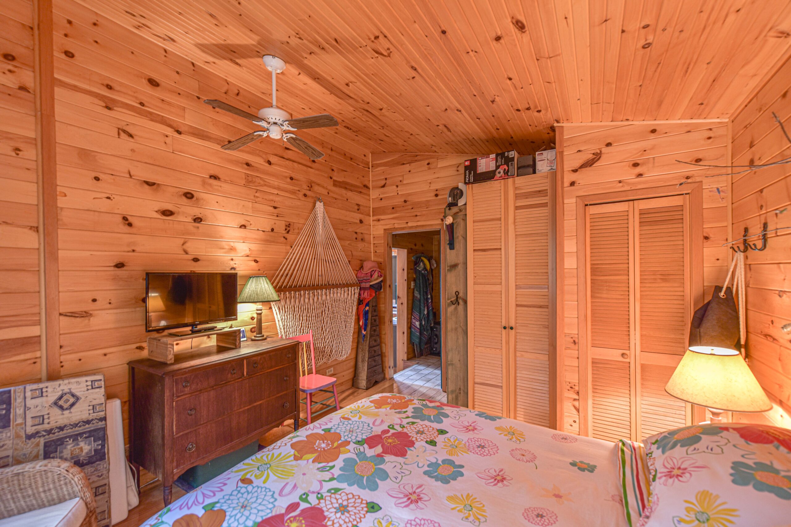 The end of a floral bed faces a dresser in a wood panelled room