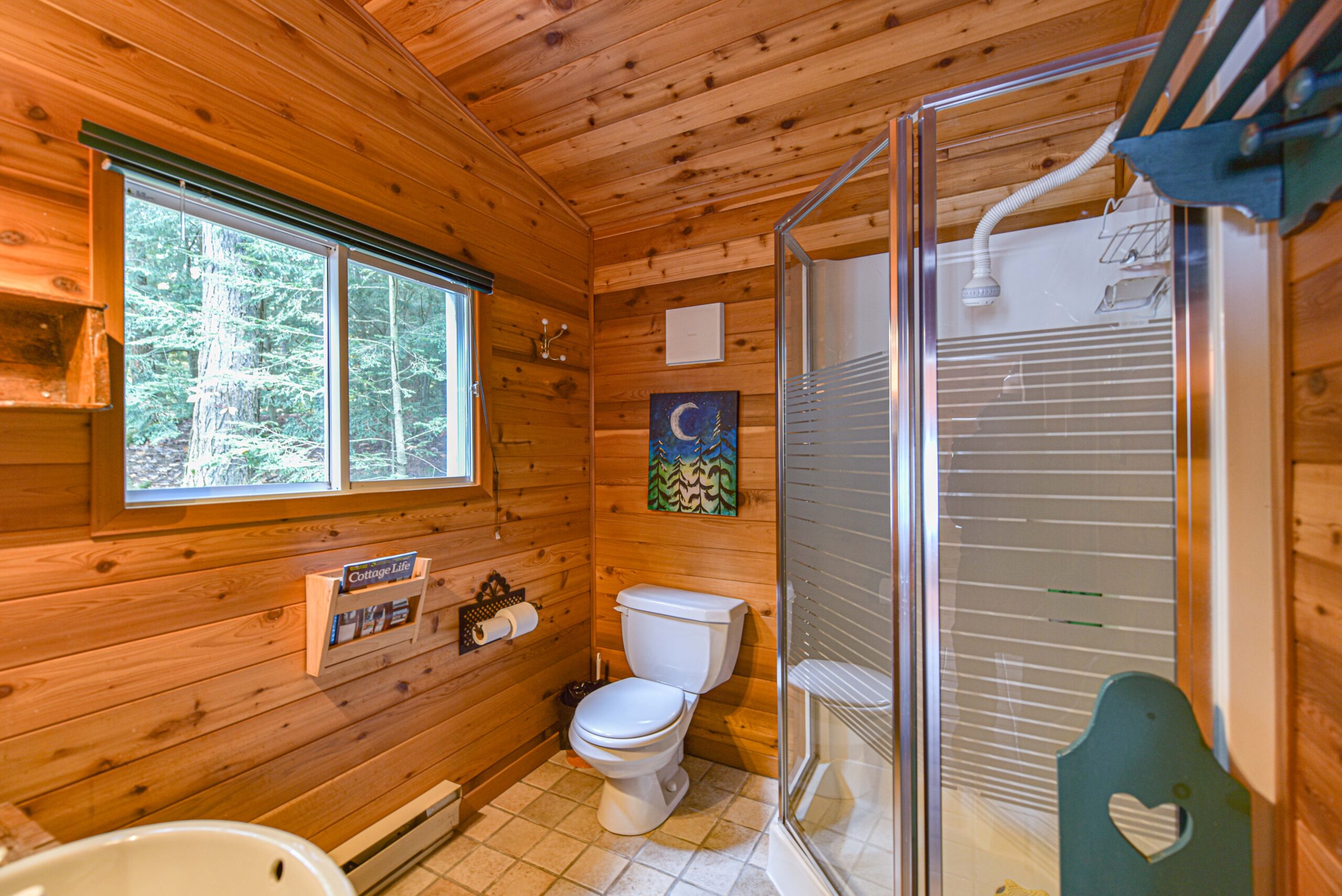 A toilet next to a glass walk-in shower in a wood panelled bathroom