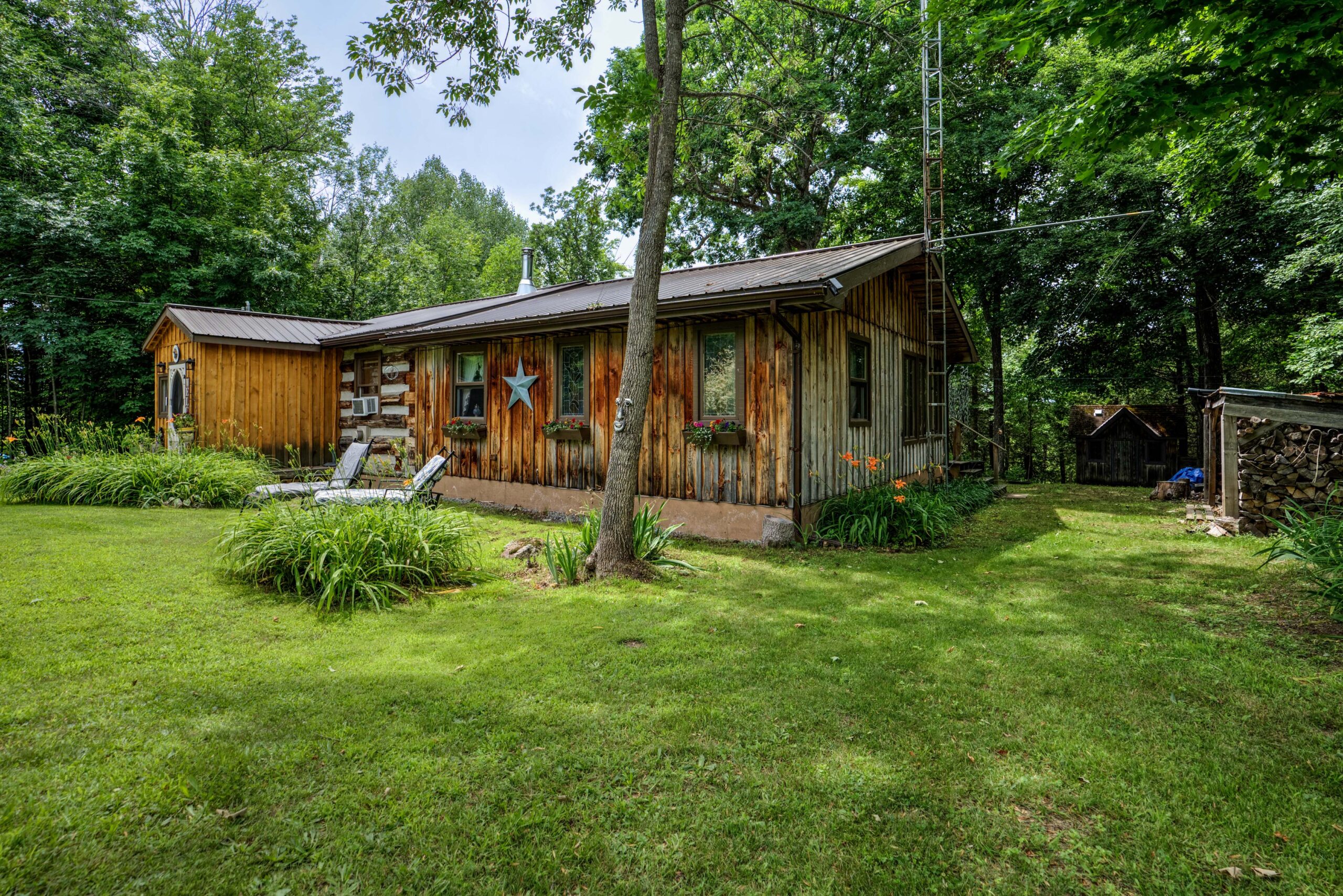 A bungalow log cabin with a large green yard