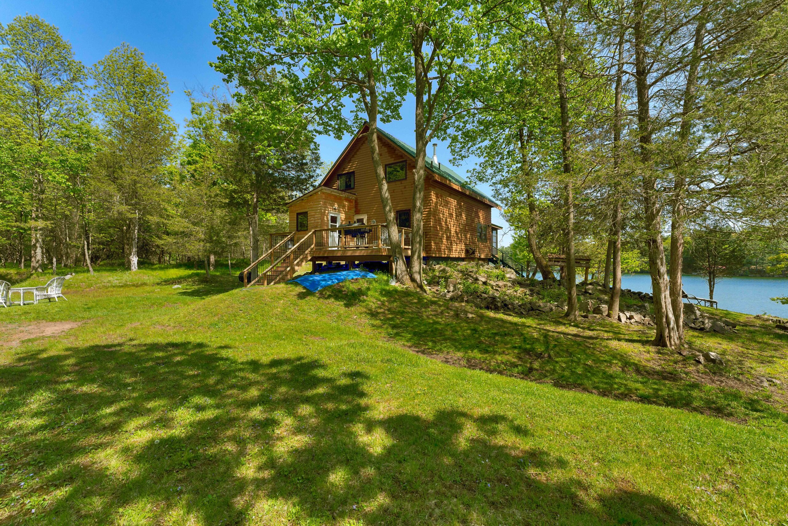 A huge grassy lawn next to the wood cottage