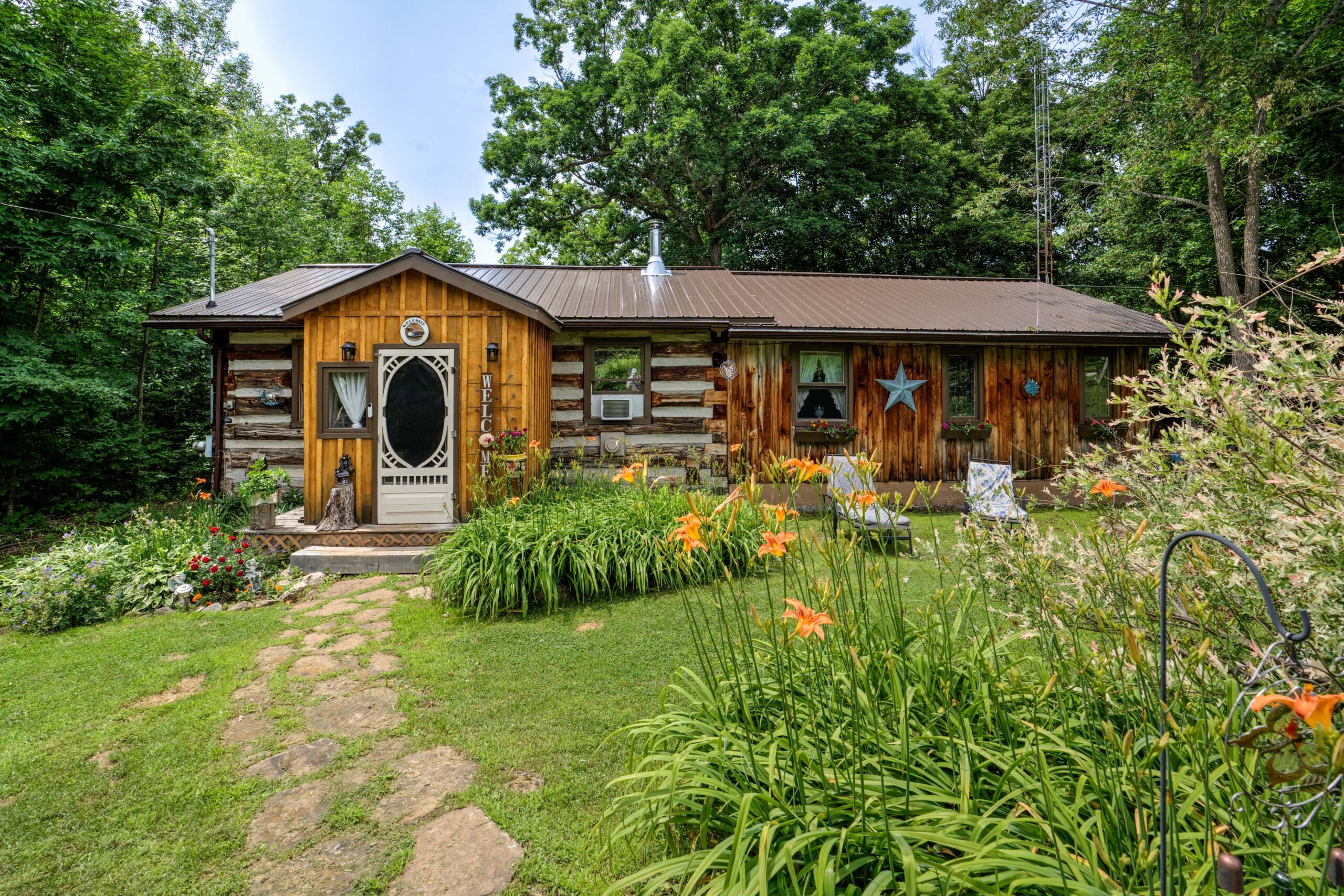 A bungalow log cabin with a large green yard
