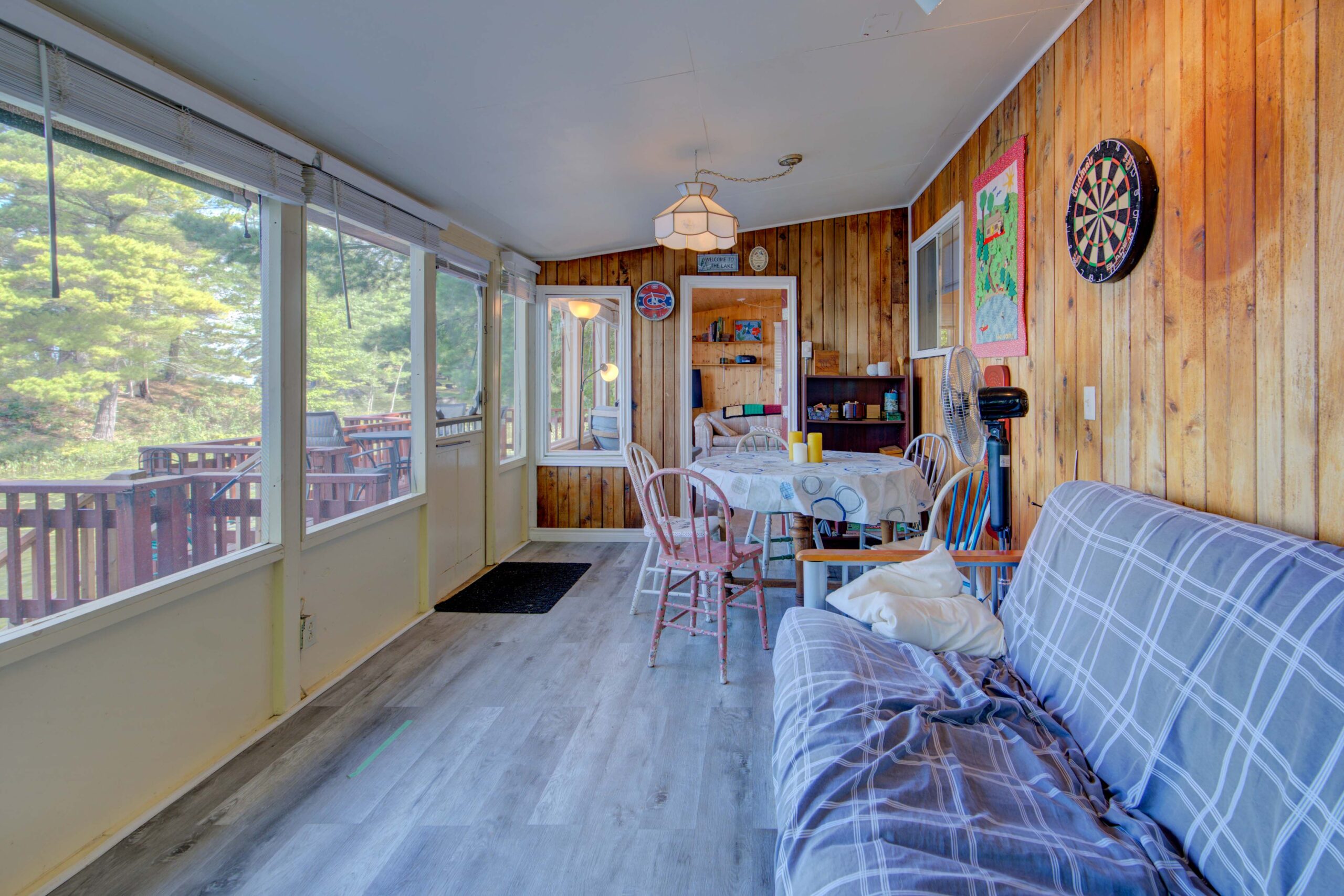 A plaid couch faces large windows in a sunroom