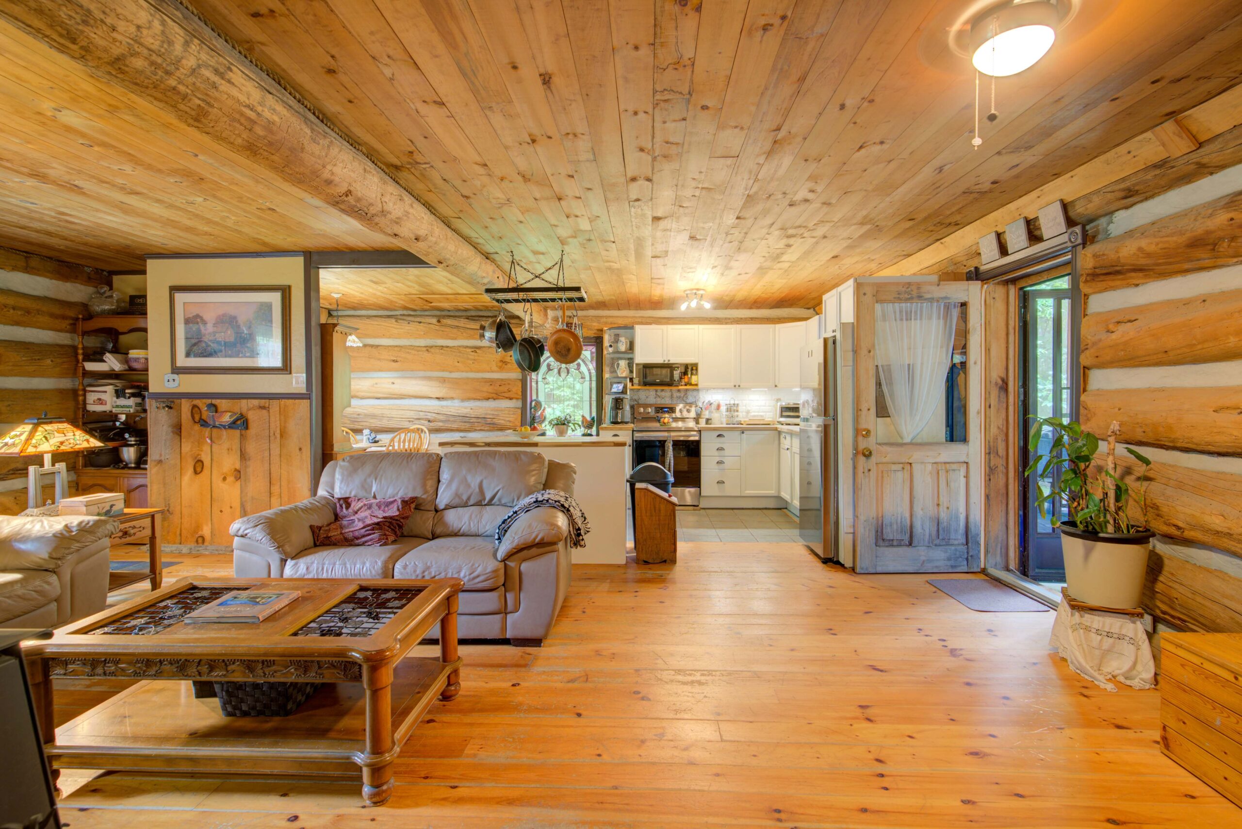 A wood-paneled room with a beige couch facing a wood table