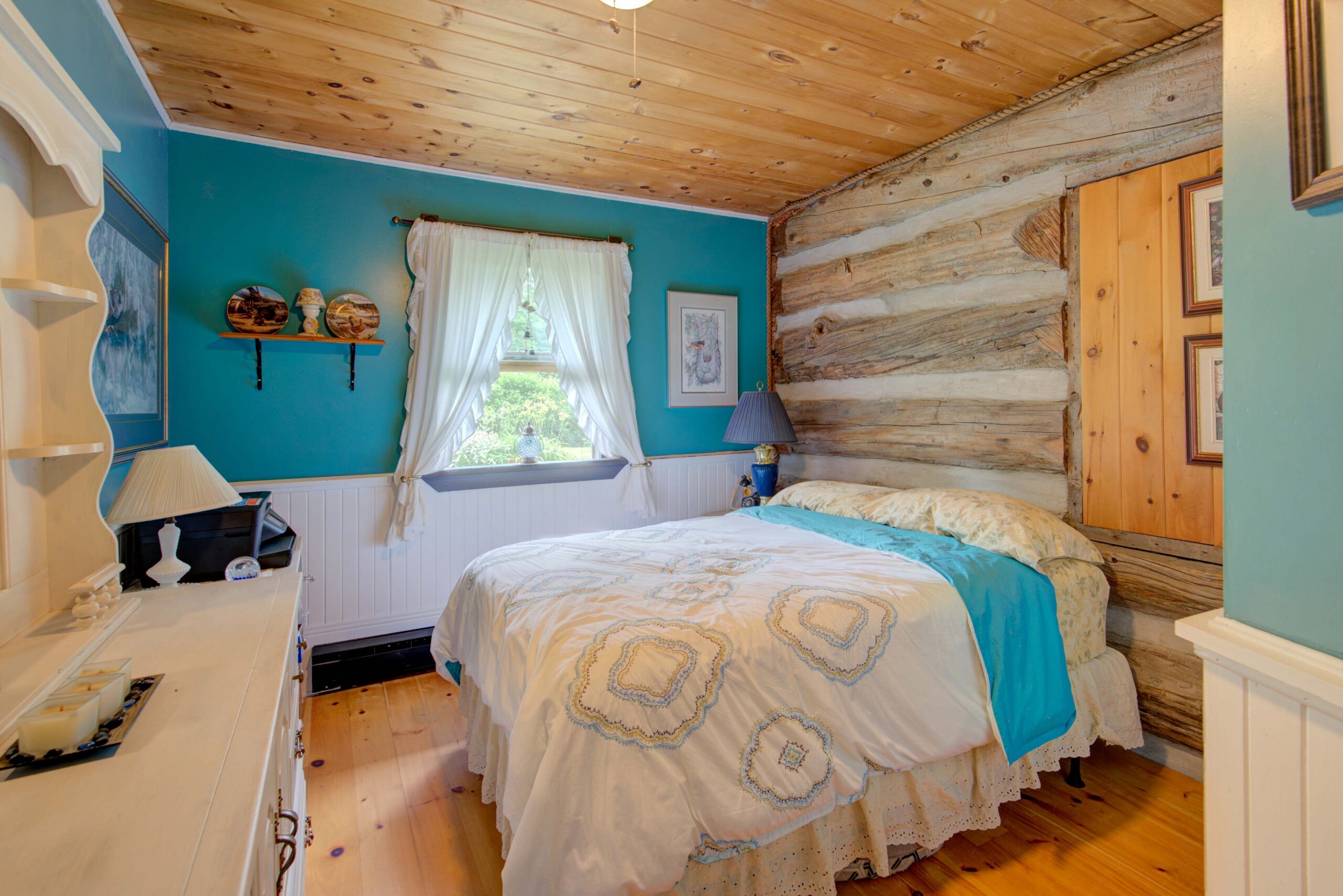 A large bed in a wood-paneled room. The wall beside the bed is teal blue.