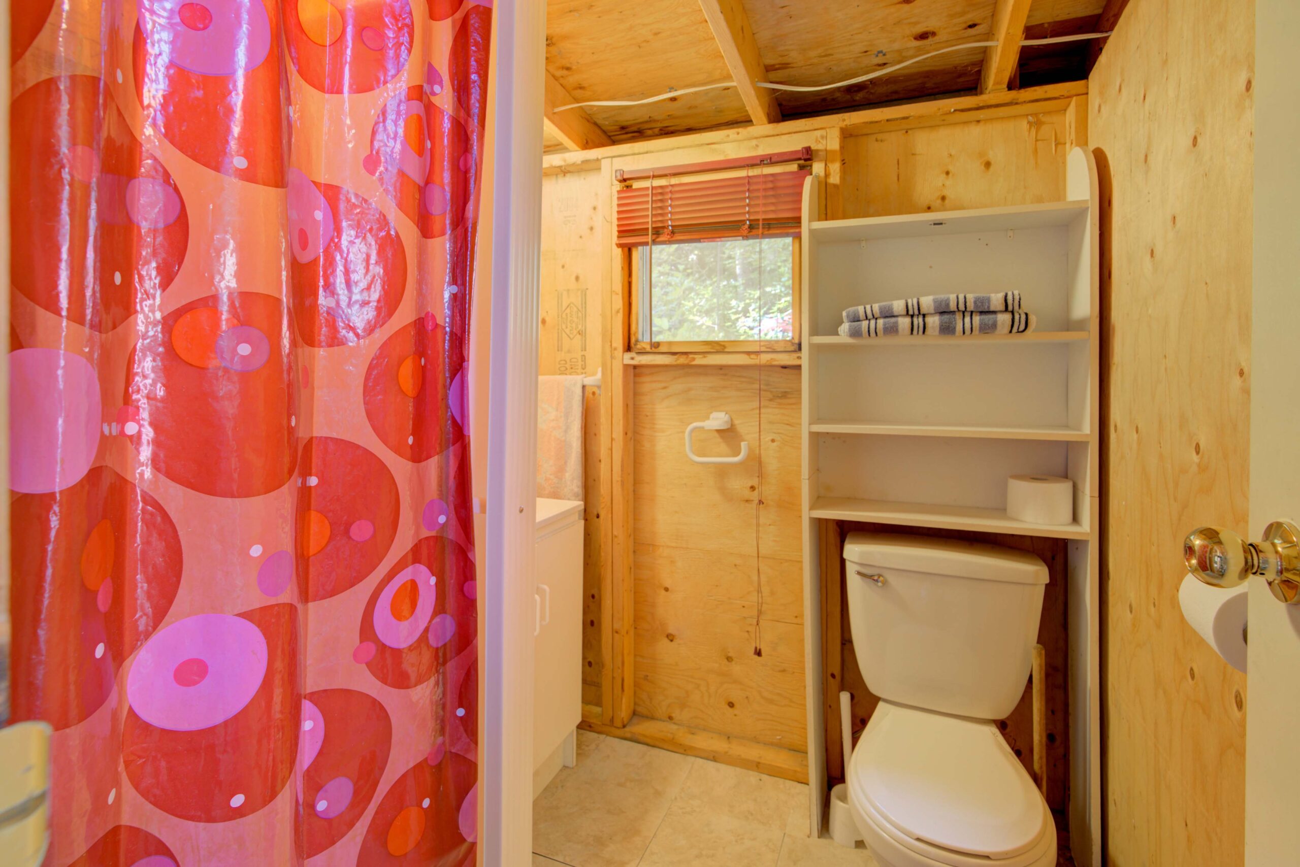 A wood bathroom with a white toilet and a pink shower curtain