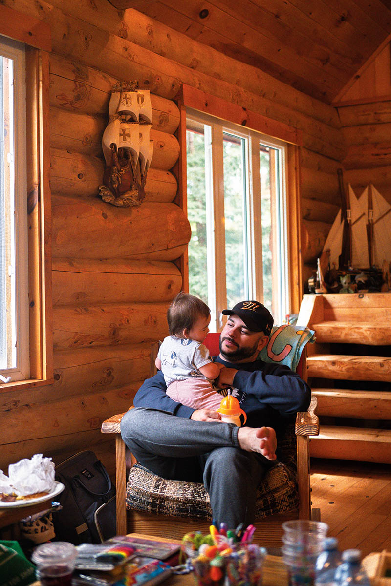 A family member sits with their young child inside the cottage
