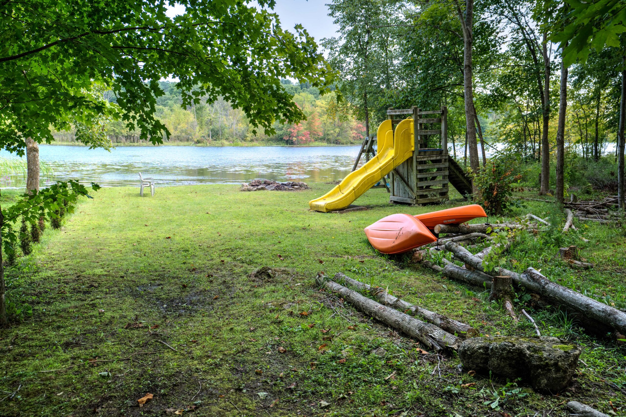 A large grassy area with the creek in the distance and a yellow slide