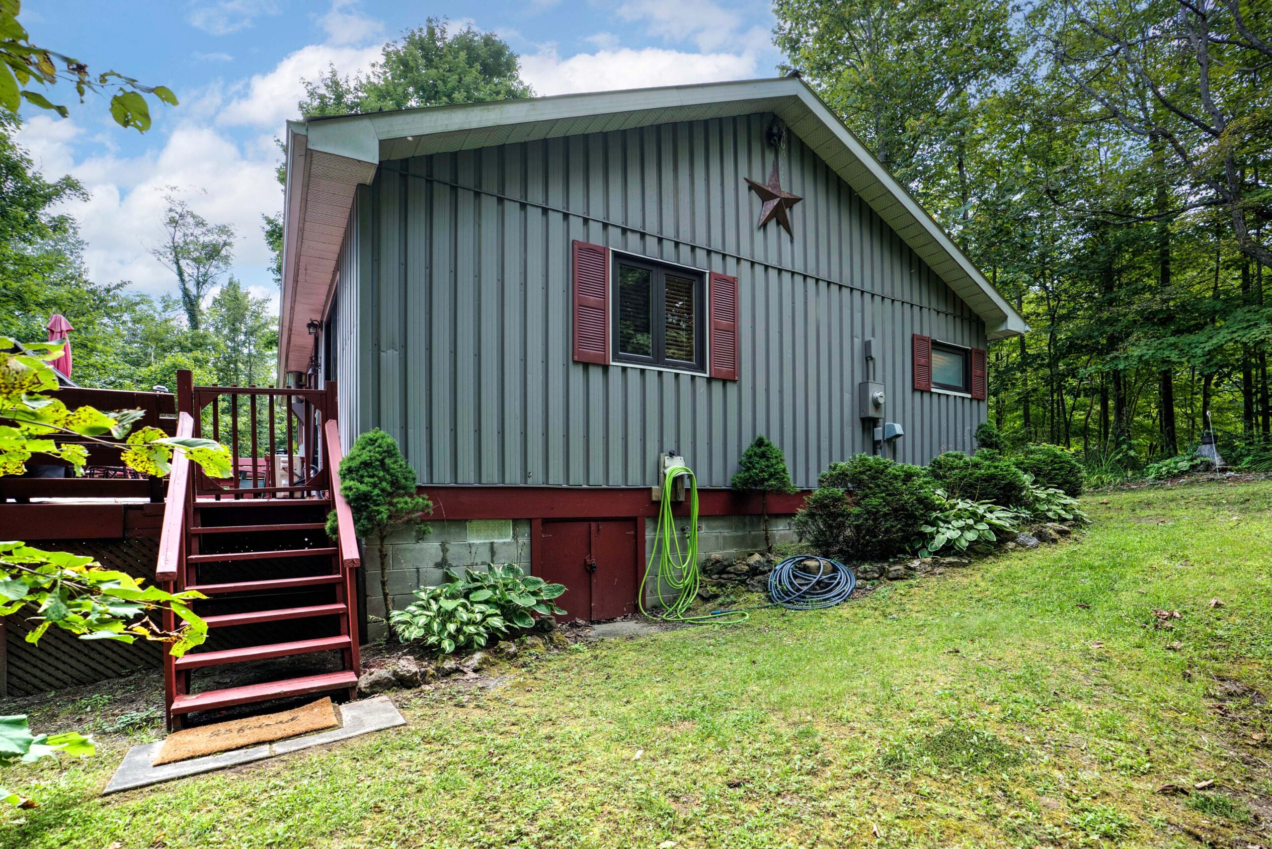 The side of the grey cottage with red trim