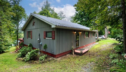 A grey panelled cottage with red trim