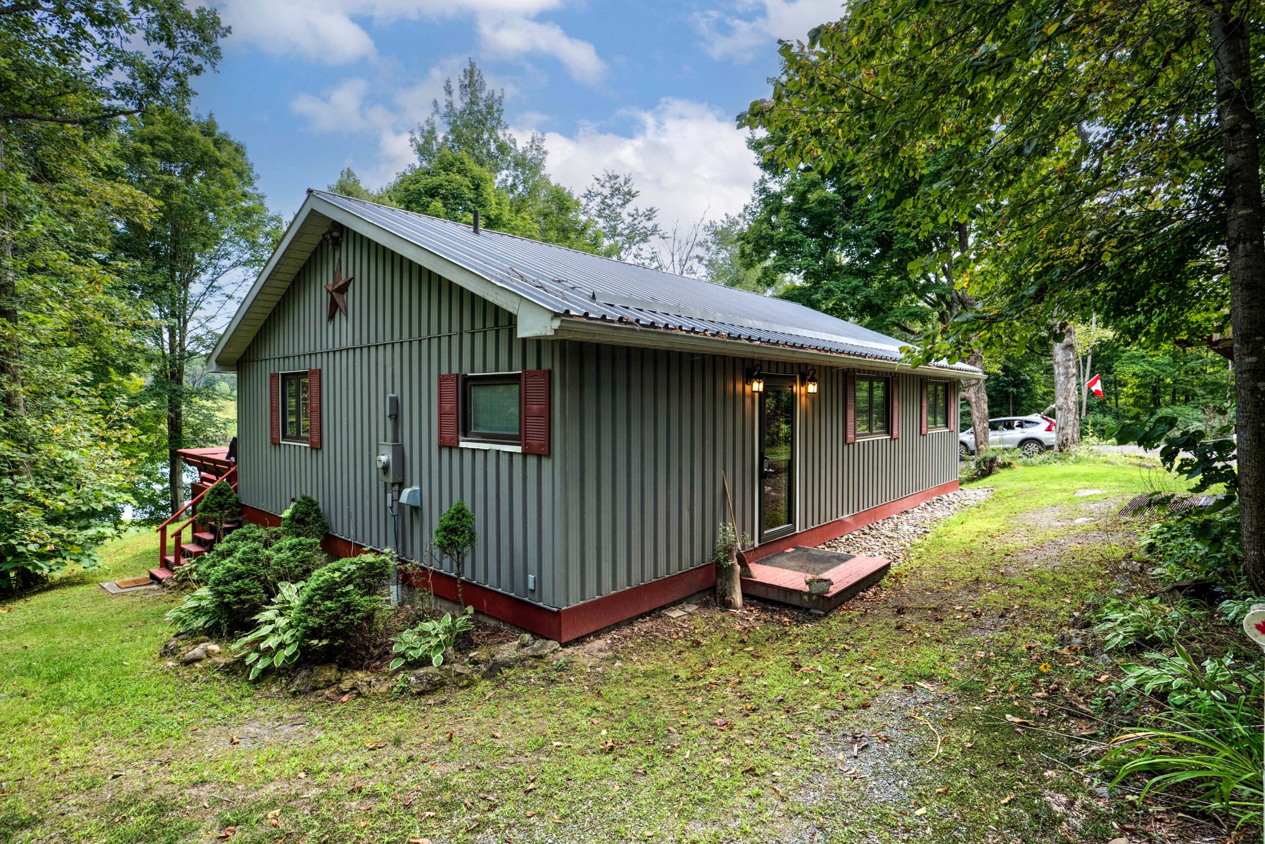 A grey panelled cottage with red trim