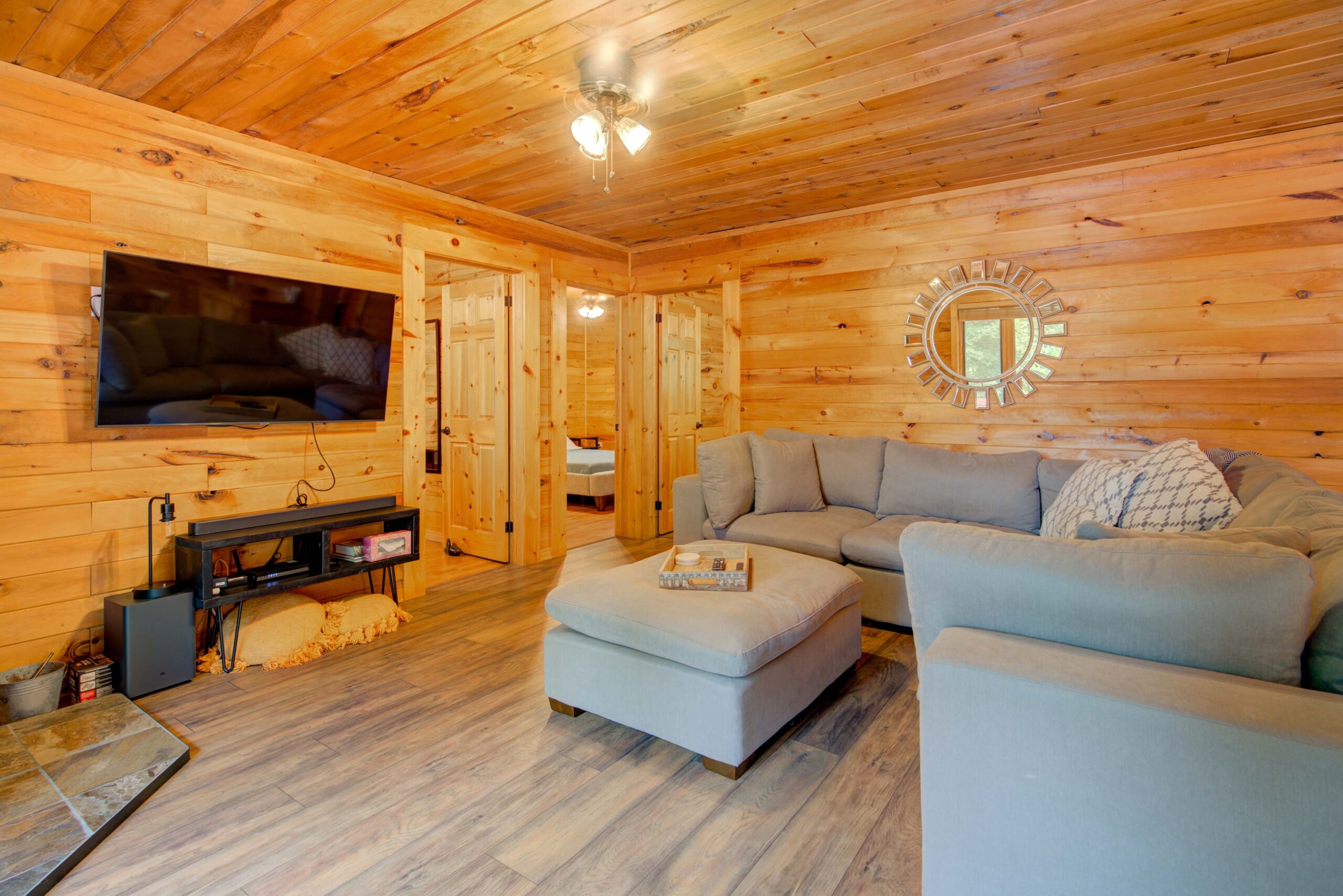 A L-shaped couch faces a wood-panelled wall with a flat-screen TV