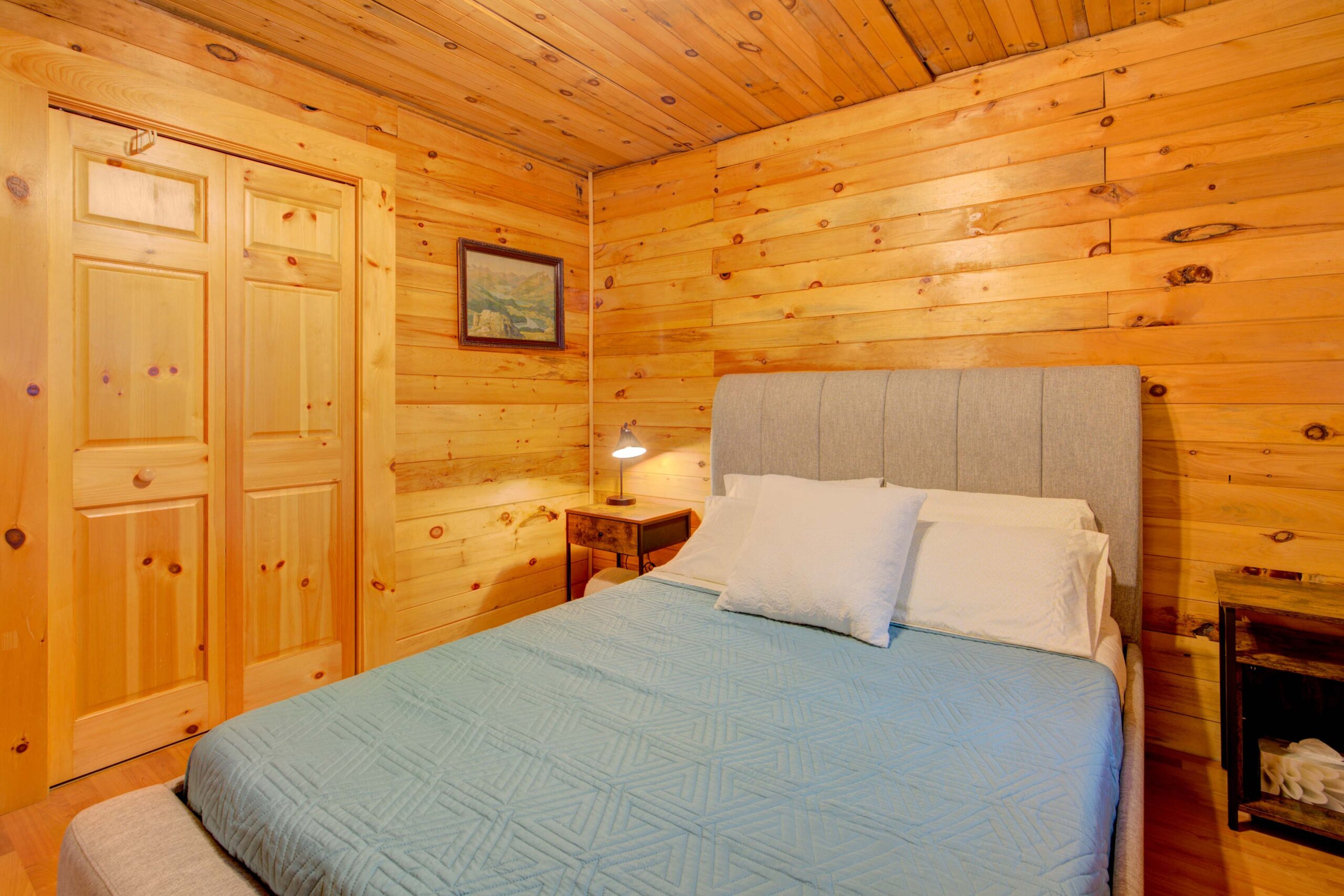 A blue bedspread on a bed in a wood-panelled room