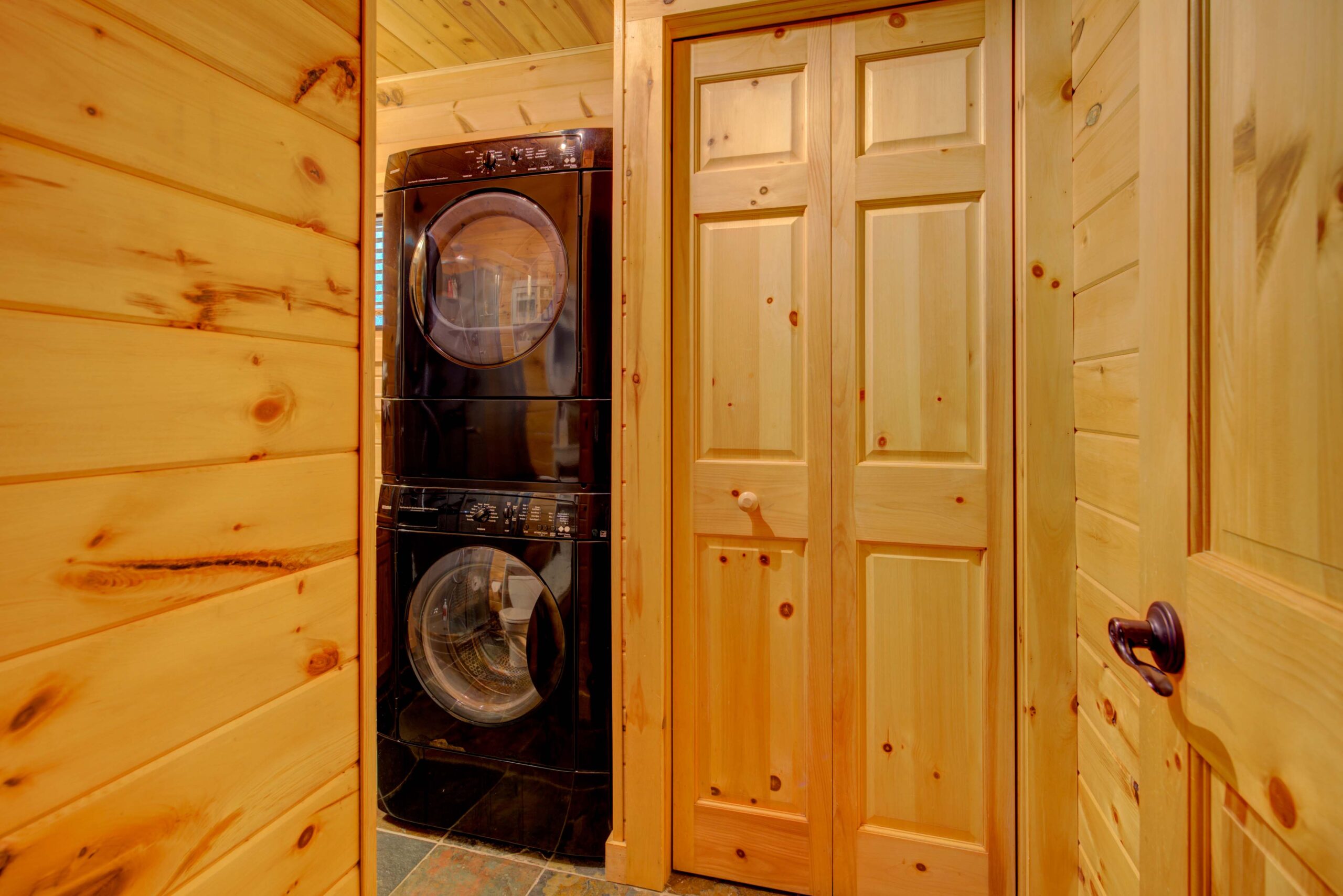 Stacked black washing machines next to a wood door