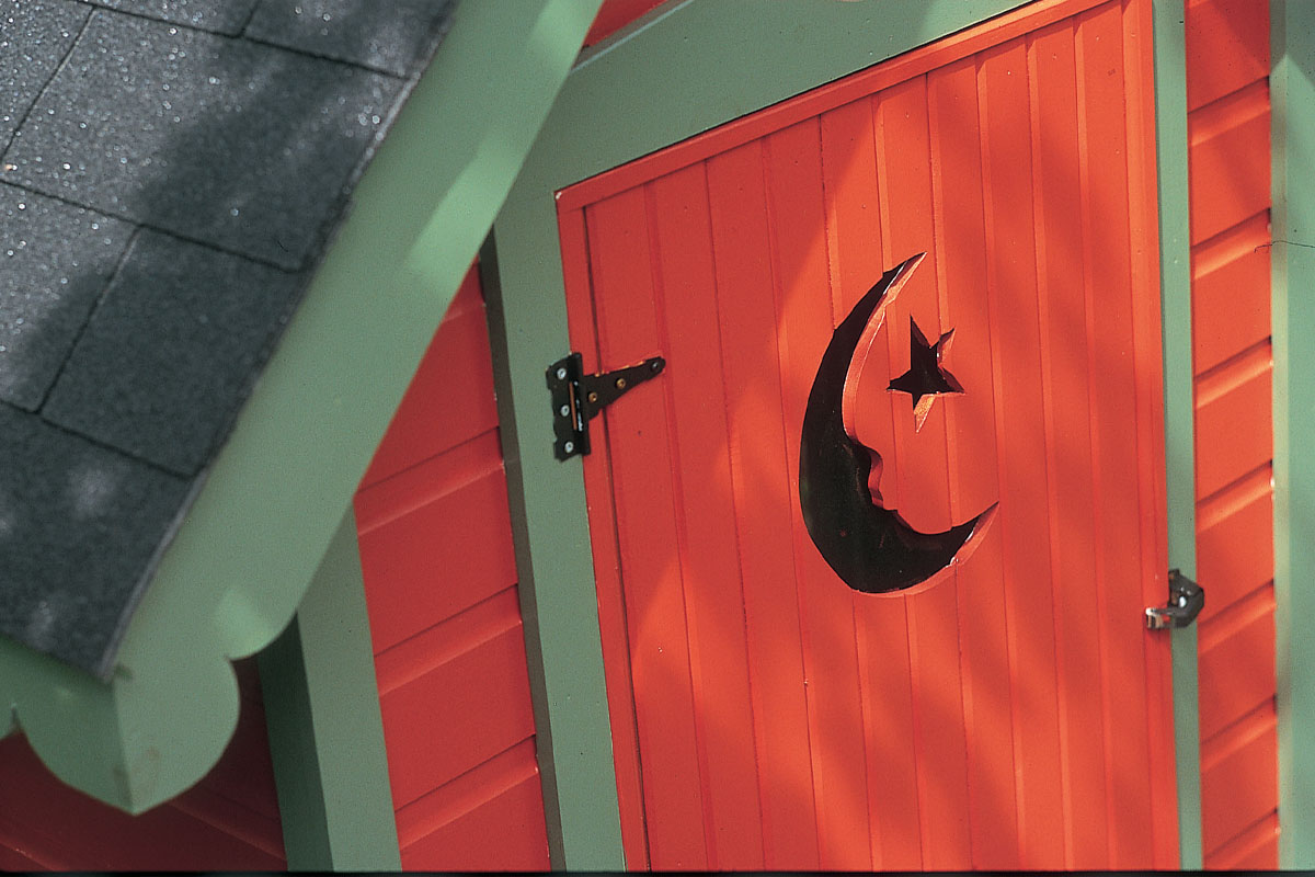 A close up of the crescent moon and star on an outhouse door