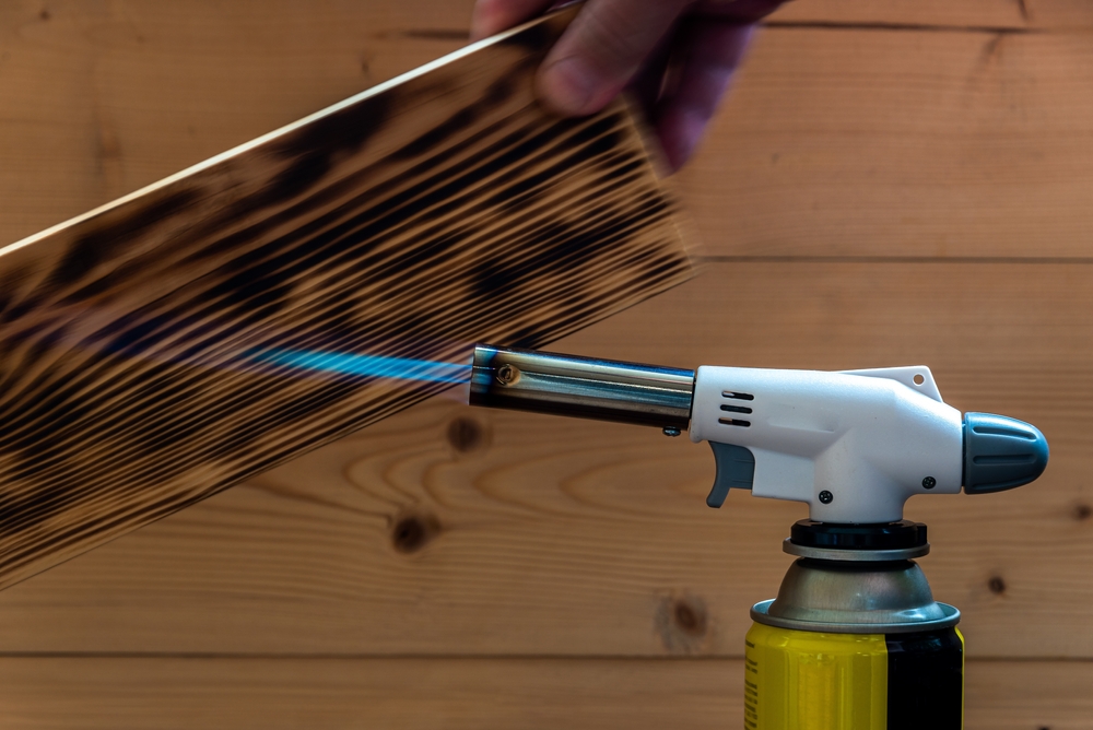 A gas torch burning a piece of wood
