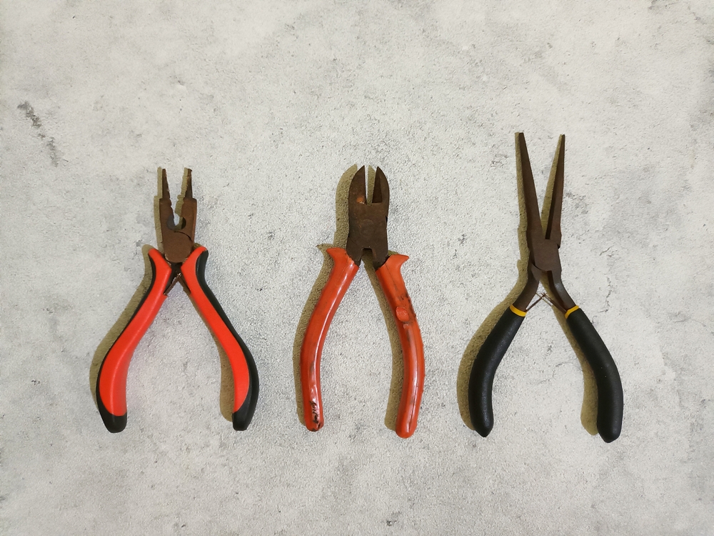 Three sets of pliers against a grey background