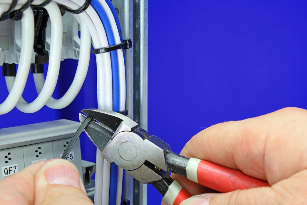 A hand using wire cutters to cut a wire