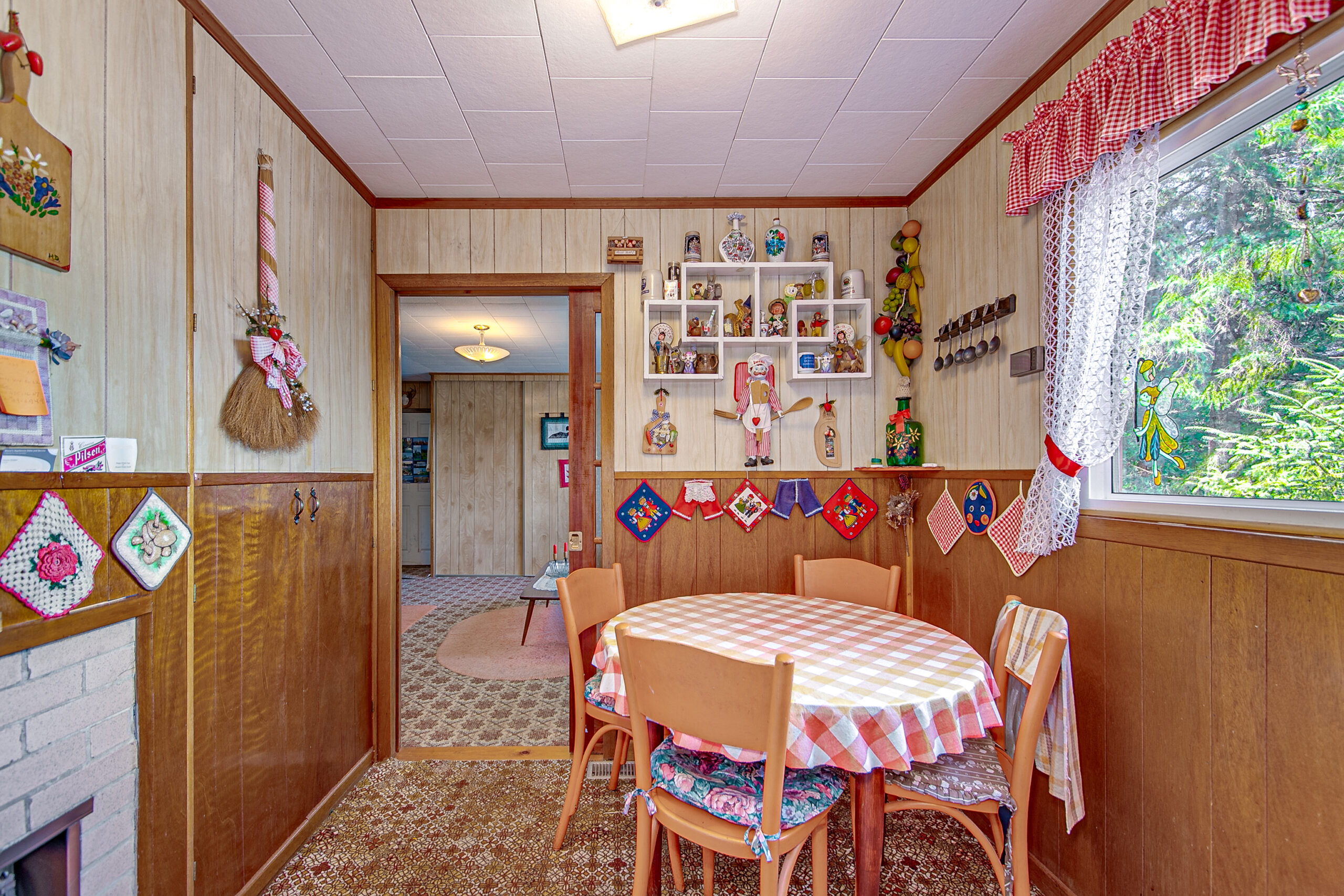 A round dining table with a red and white checkered tablecloth in a small kitchen