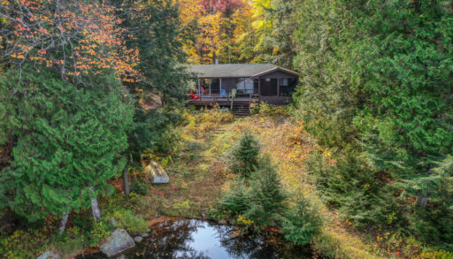 A brown bungalow cottage surrounded by fall trees