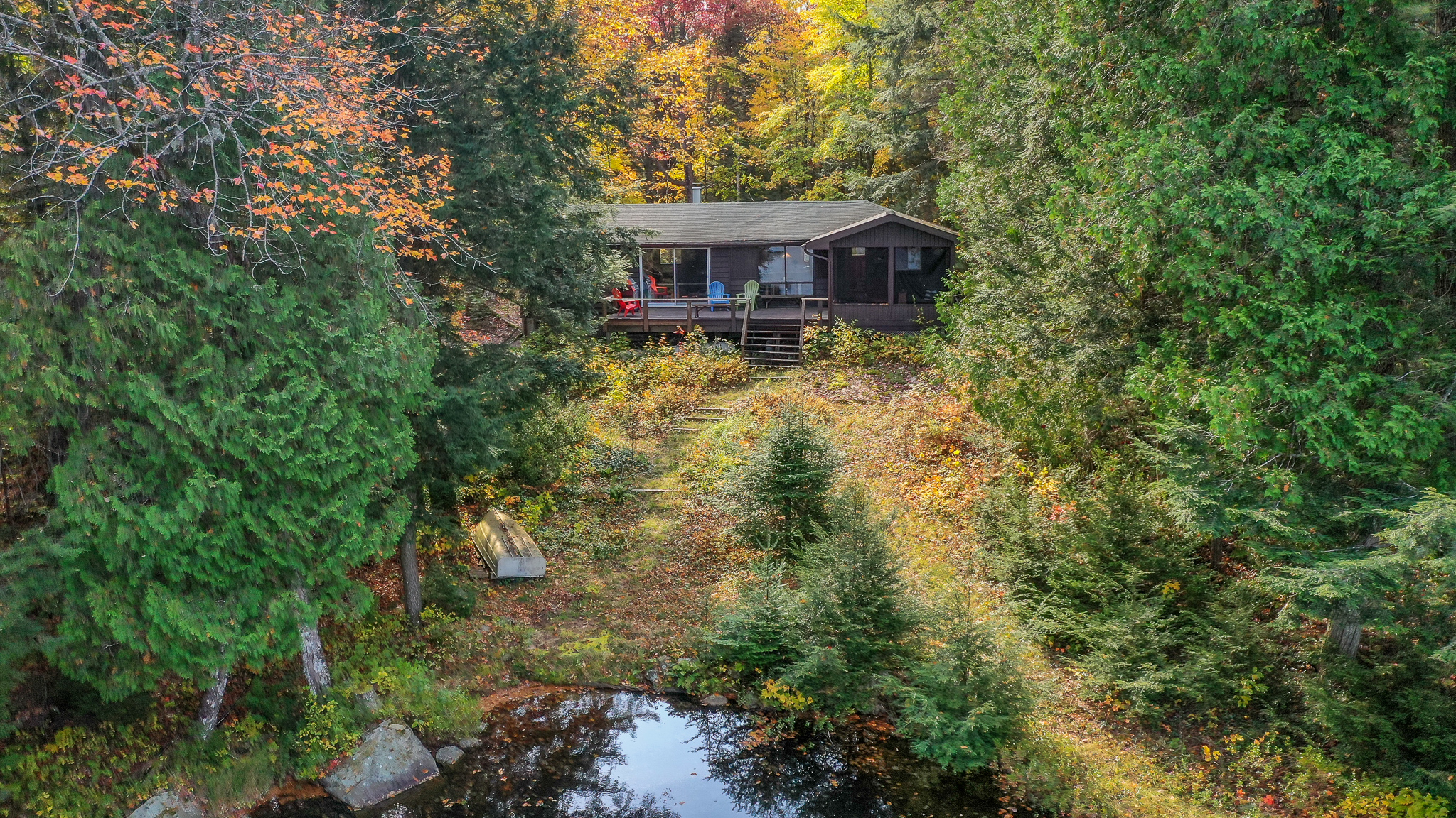 A brown bungalow cottage surrounded by fall trees