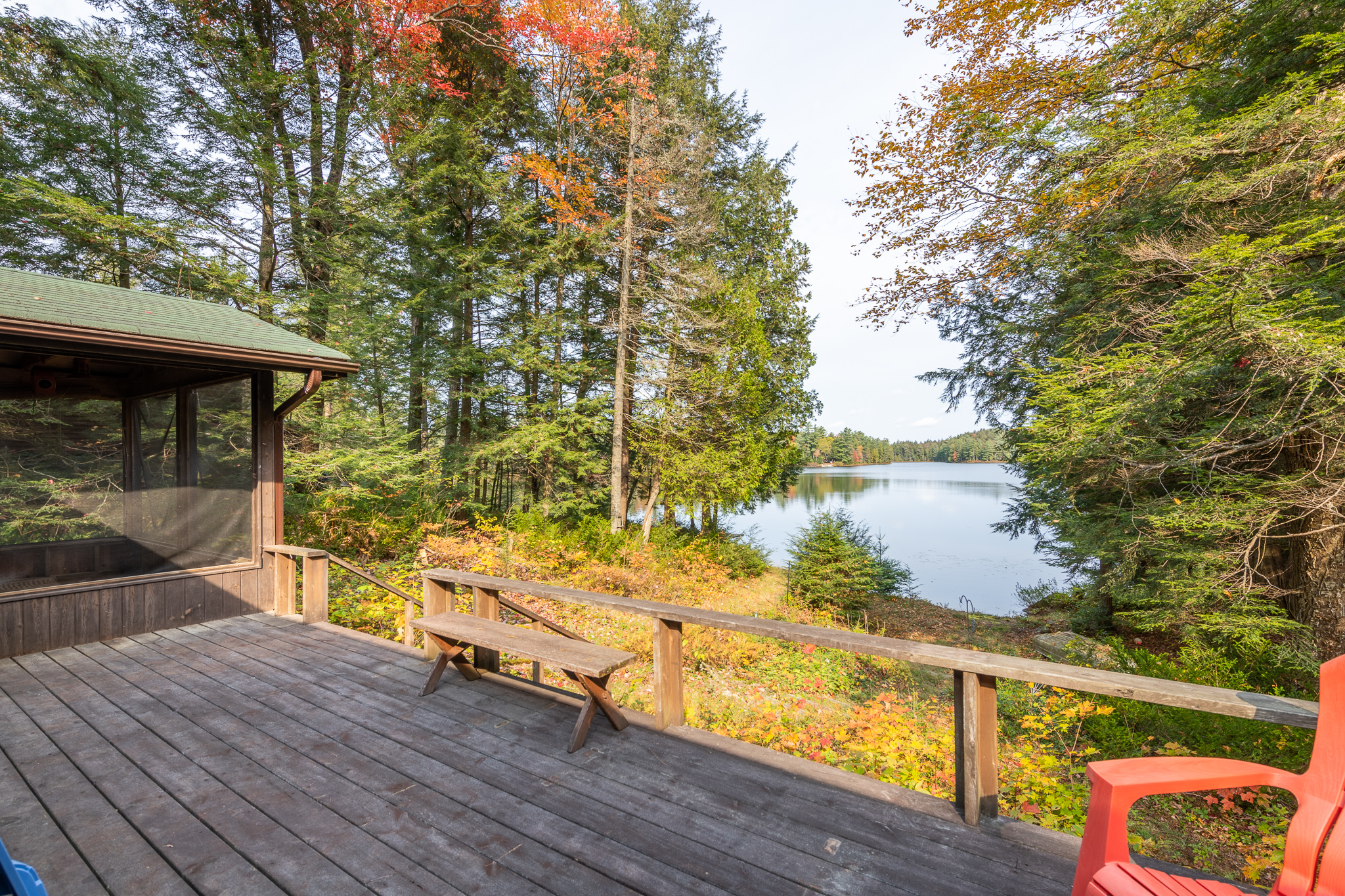 From the grey-brown deck, a blue lake surrounded by fall foliage