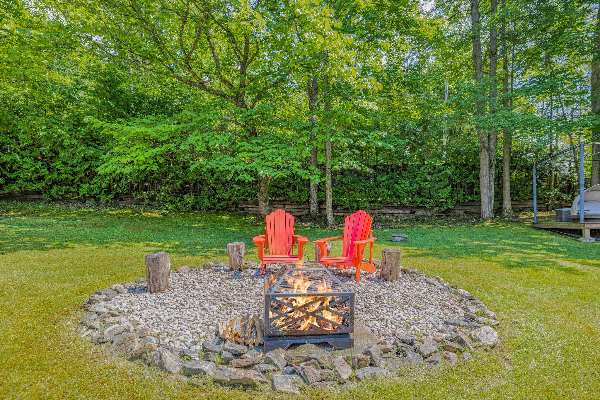 A fire pit with two red Muskoka chairs