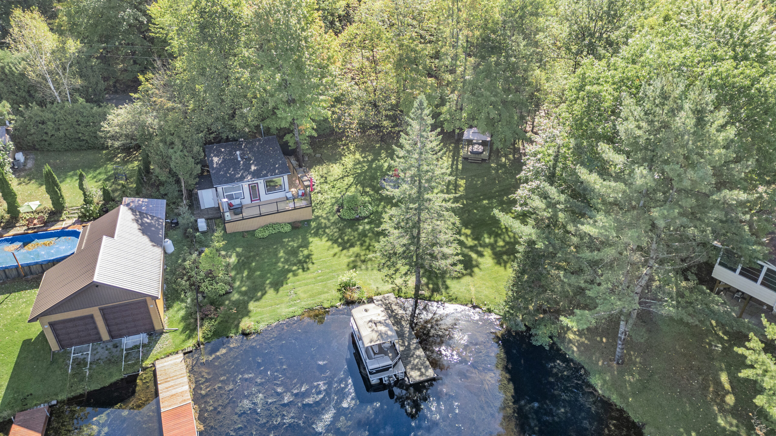 Aerial view of a white cottage near a lake with a boat