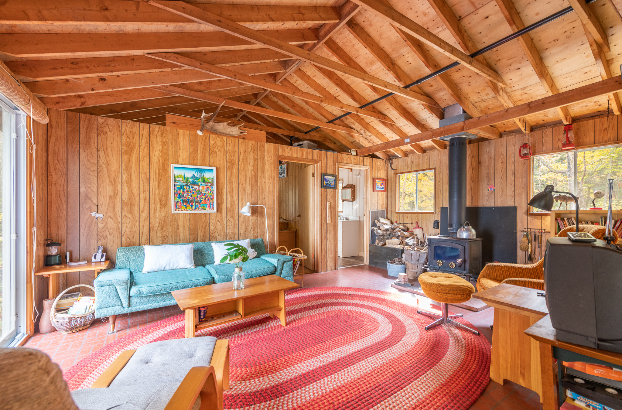 A wood living room with vaulted ceilings and a large round red carpet