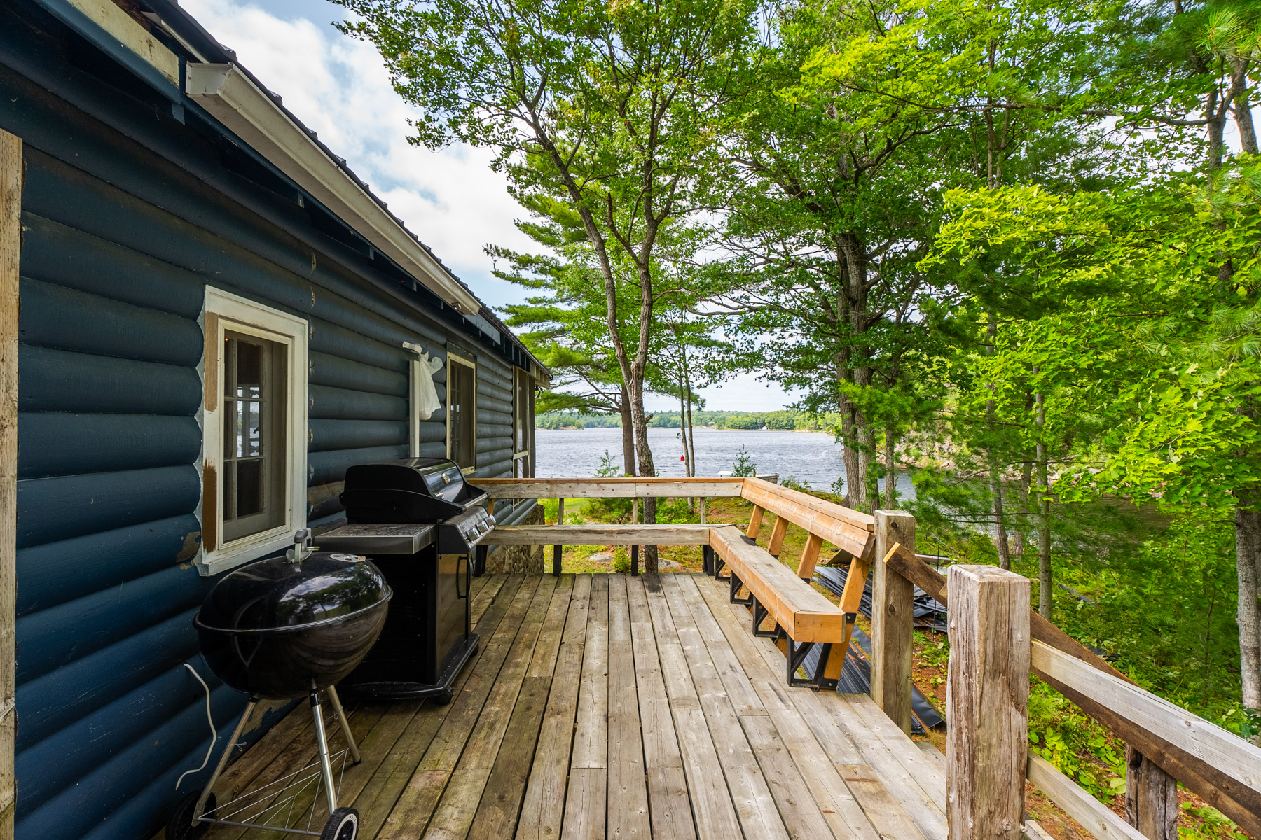 A wood deck along the side of a blue cottage