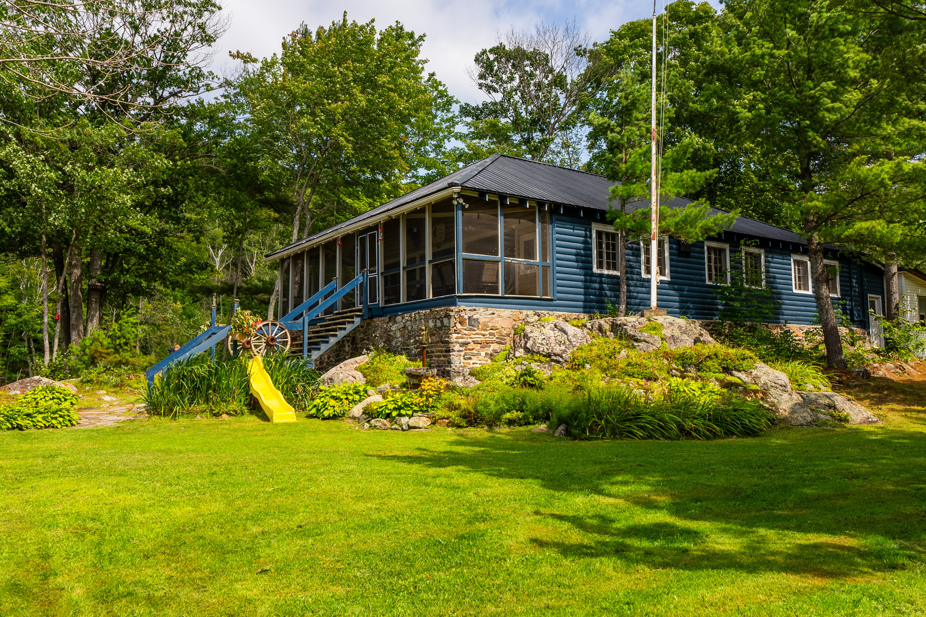 A large blue cottage with a stone foundation