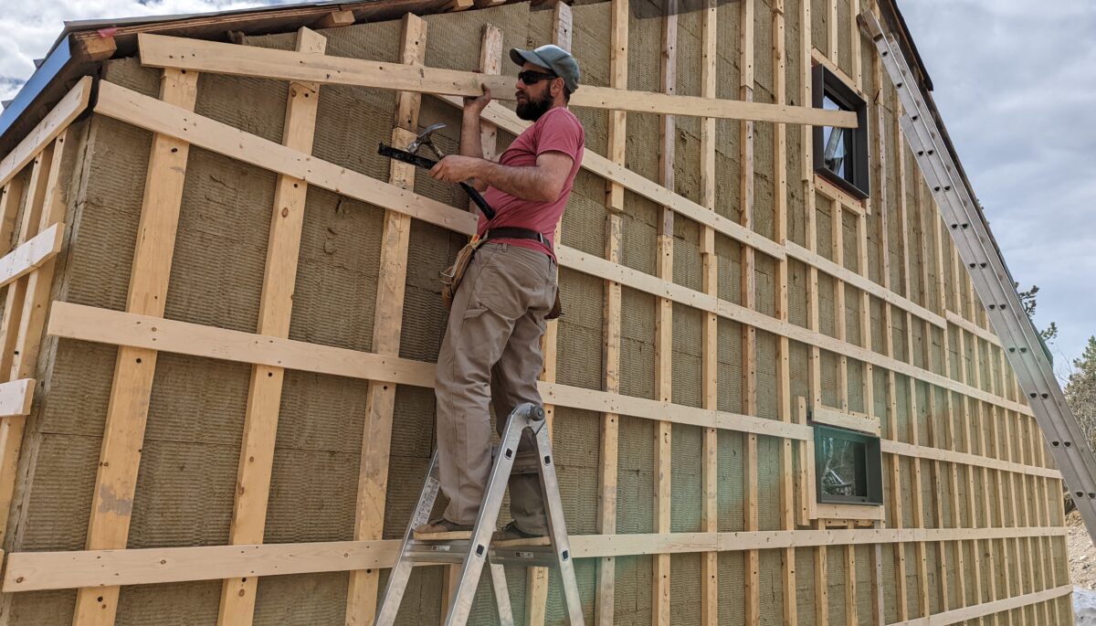 A man standing on a ladder, working on the side of a structure