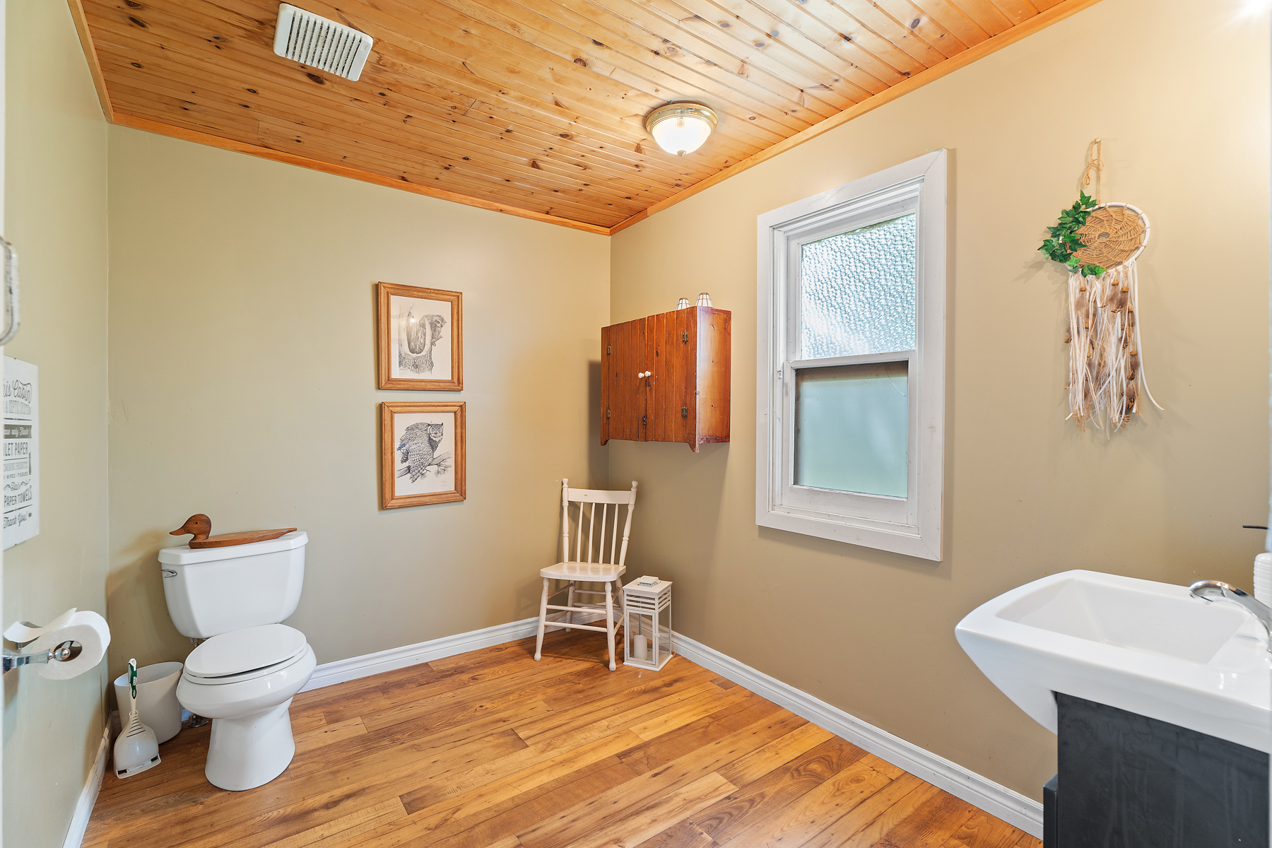 A beige bathroom with a white toilet across from a sink