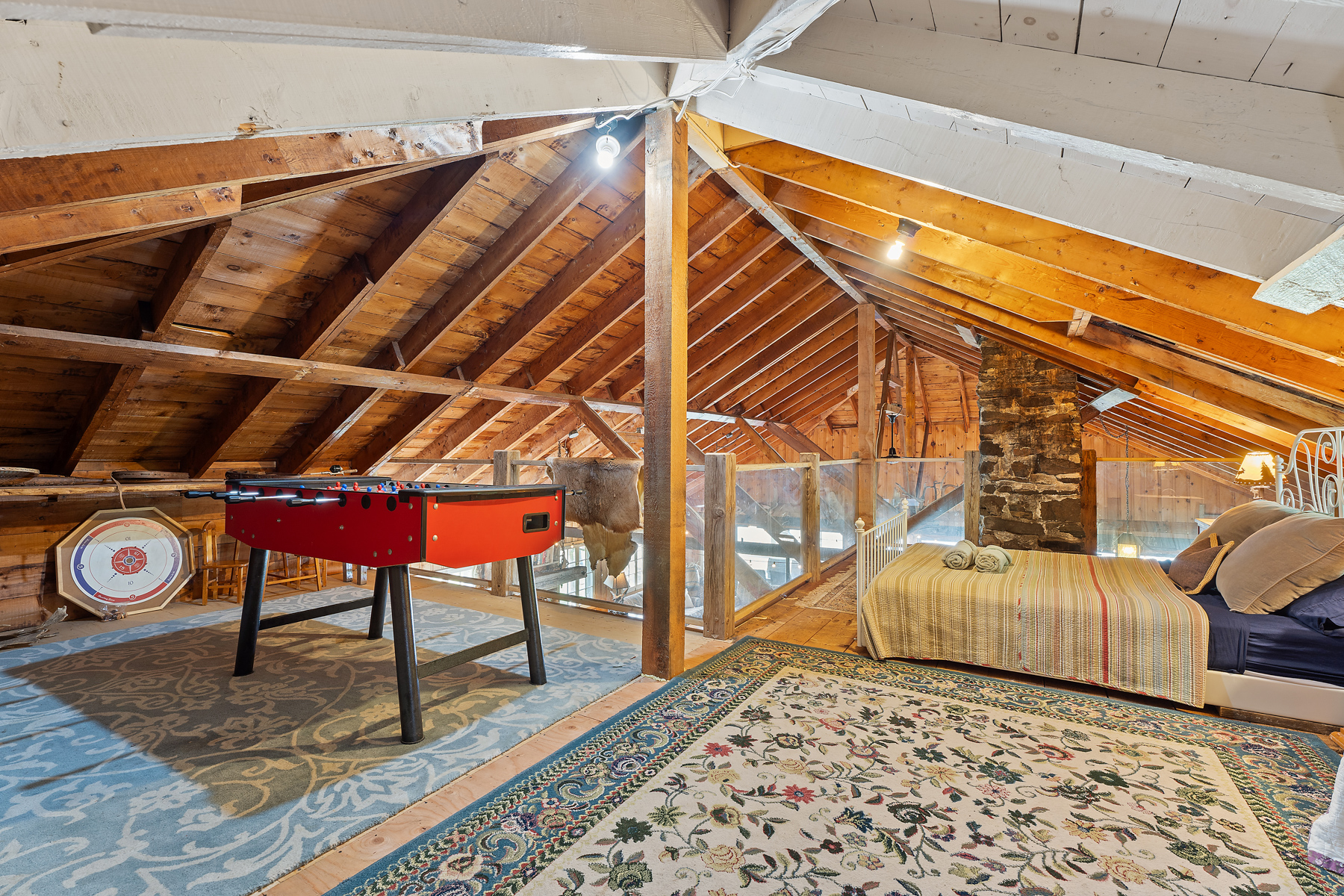 An unfinished upper loft with a red fuse-ball table and a bed