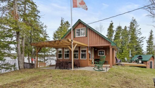 A two-story log cabin with a wood pergola
