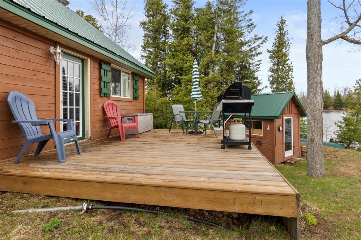 A wood deck at the back of a log cabin