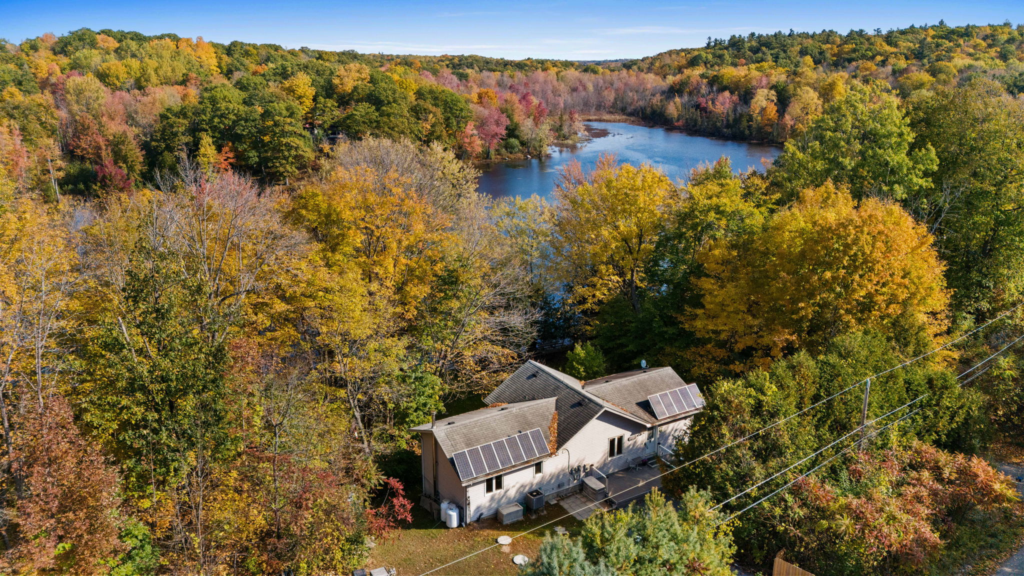 Overhead view of a grey cottage nestled amongst autumn trees