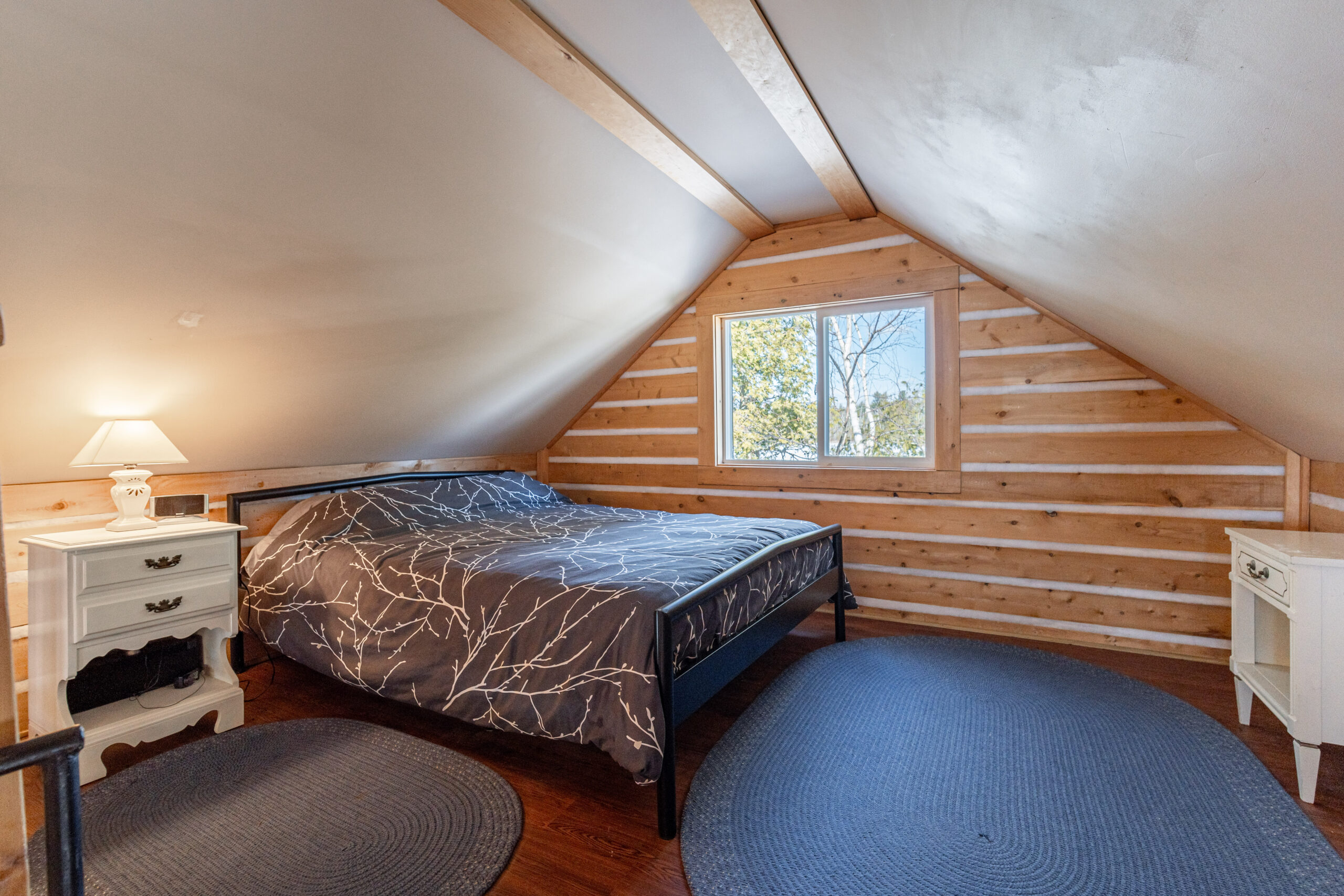 A grey bed in a log attic room
