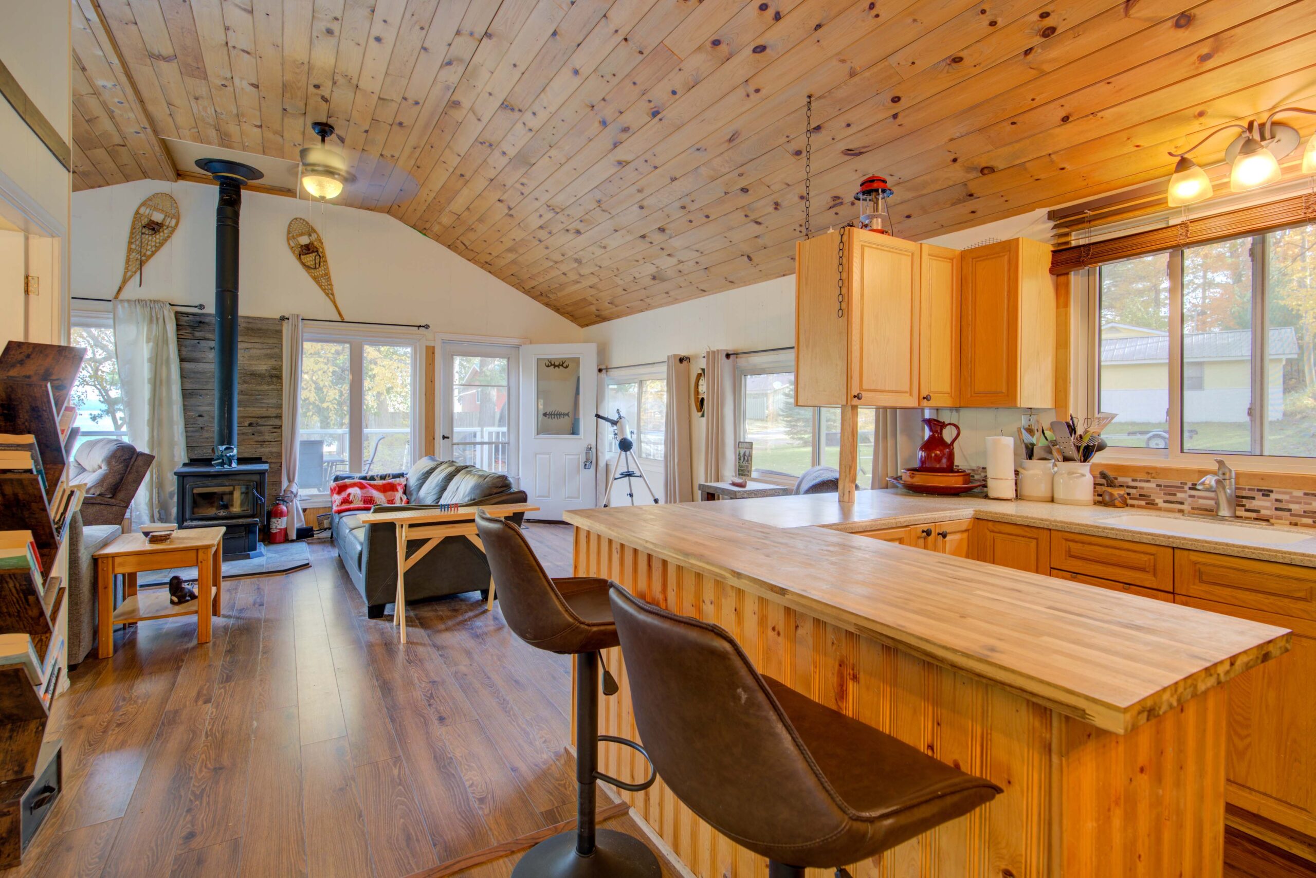 A wood kitchen with black barstools looks into the open concept living room