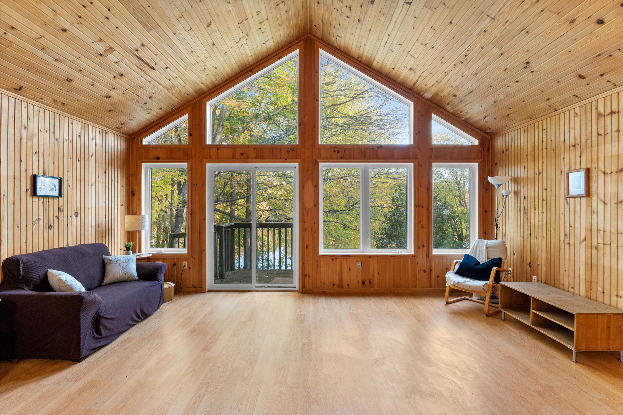 A spacious wood panelled room with vaulted ceilings and floor-to-ceiling windows