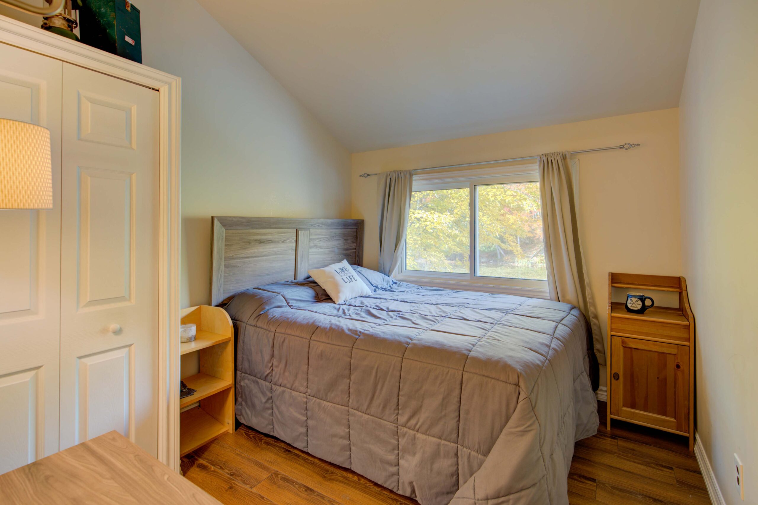 A large bedroom with a blue duvet next to a window