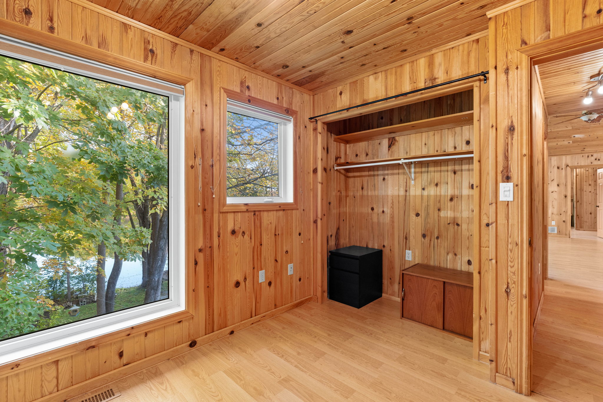 A wood-panelled room with a bright window and open closet
