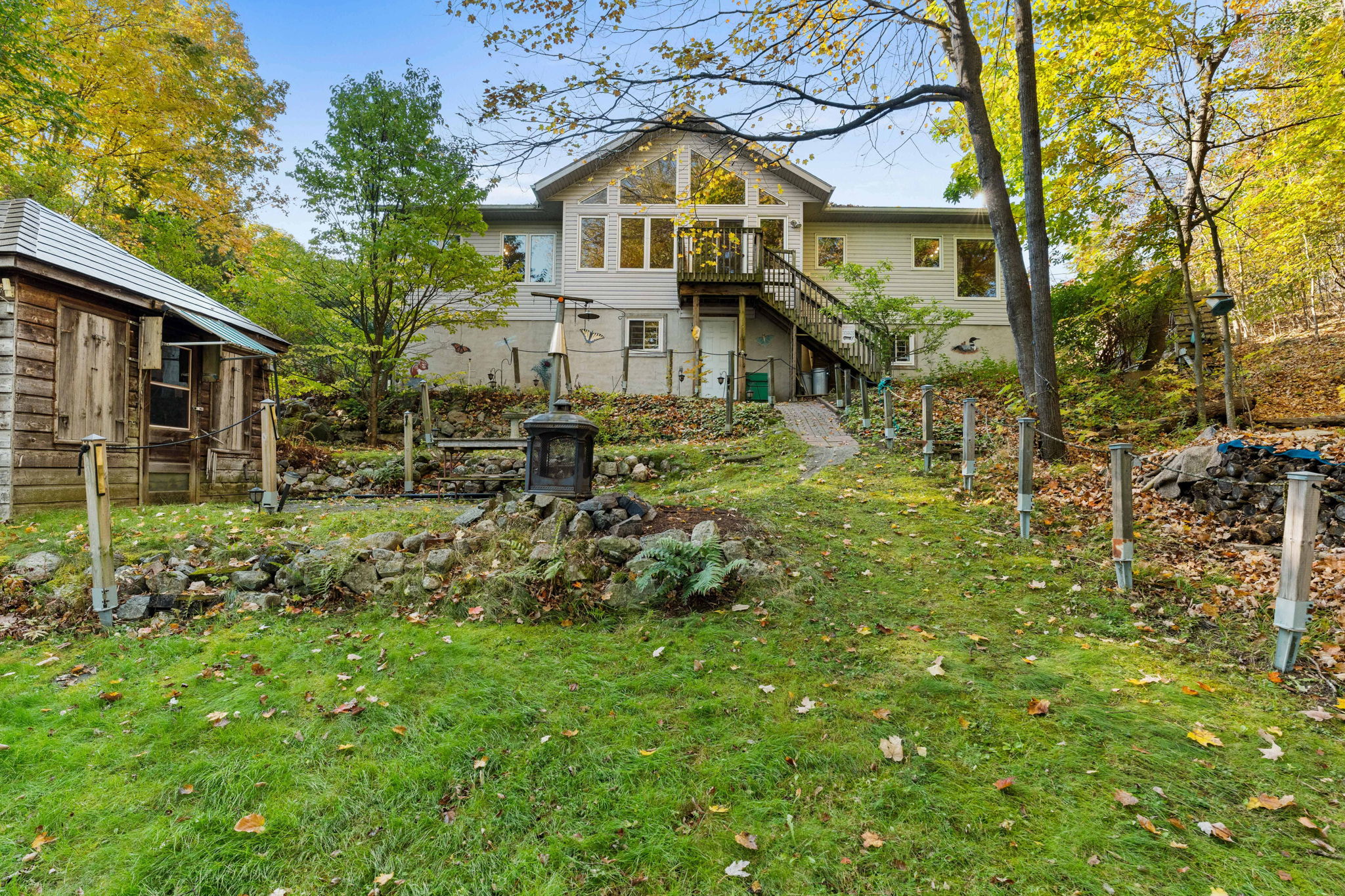 A two-story beige cottage with large windows overlooks a sprawling lawn